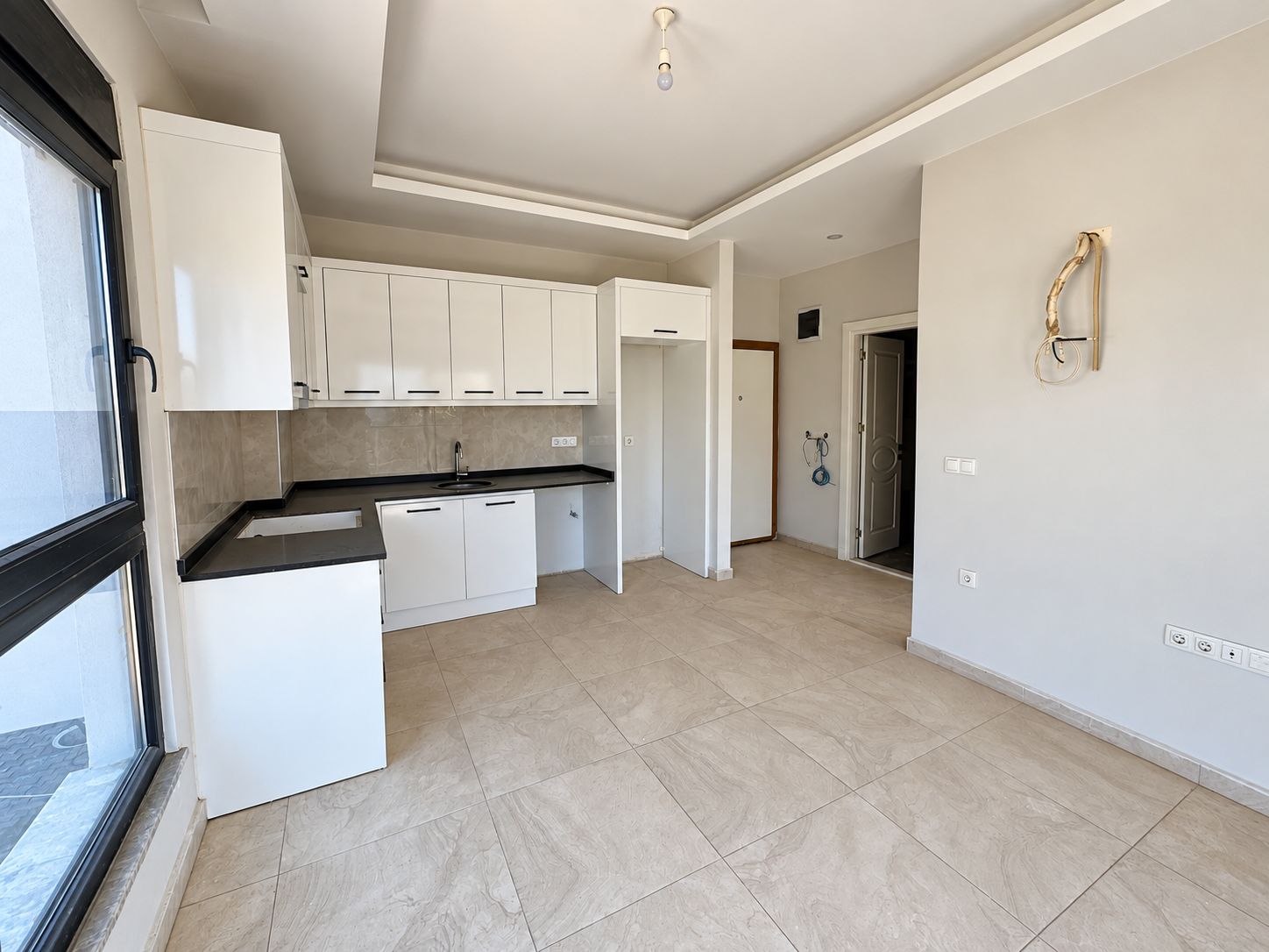 Kitchen-living room with linear white cabinetry, inset sink and black countertop in a commercial property