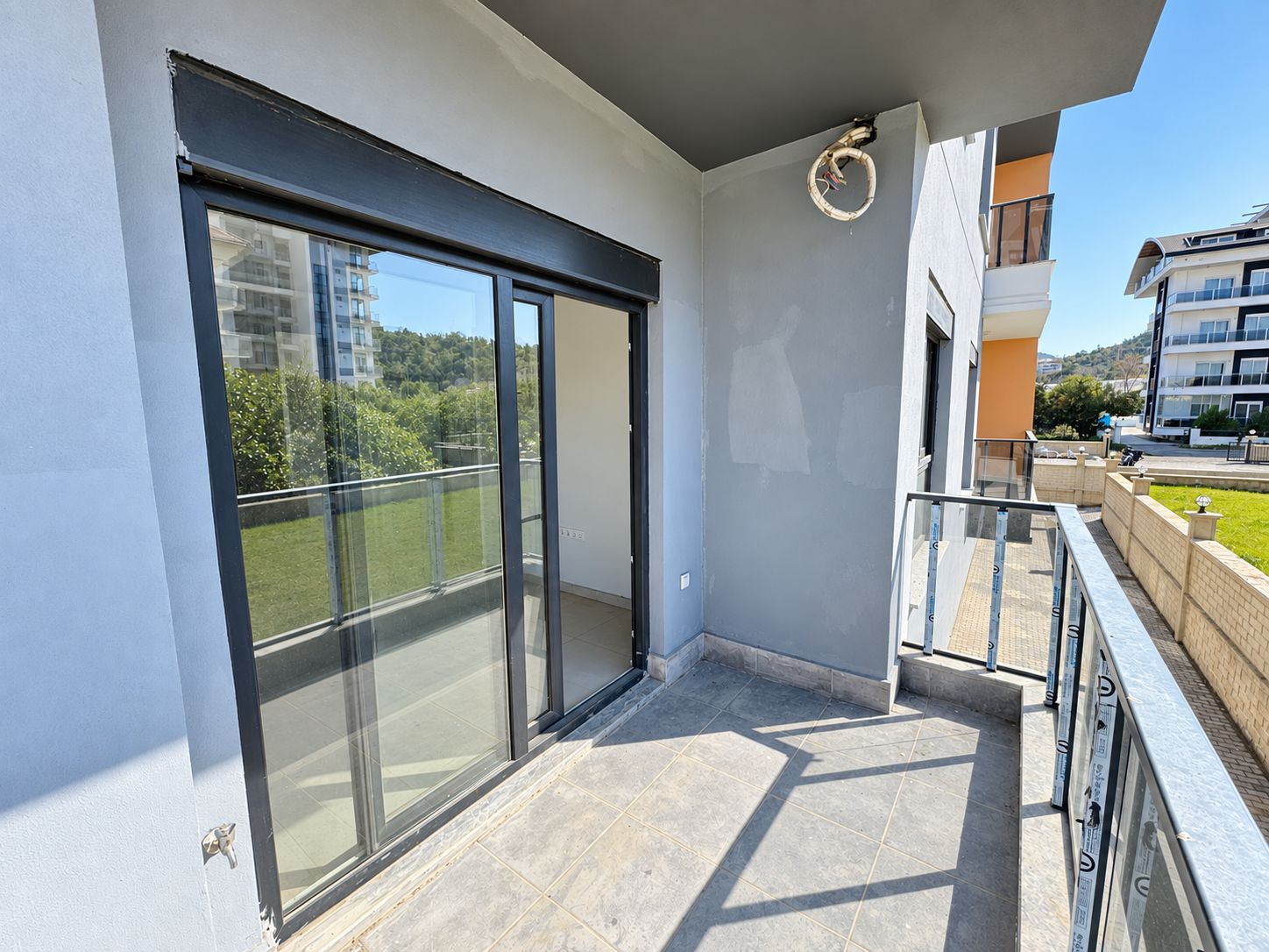 Narrow balcony with glass-panel railing and trees beyond at a commercial unit for sale in Türkiye
