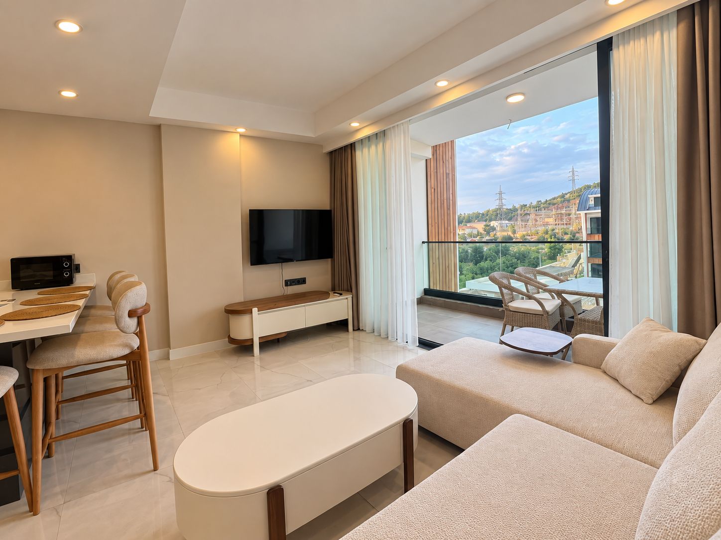 Mutfaklı salonda satılık penthouse’a ait açık renk köşe kanepe ve balkonlu panoramik pencere