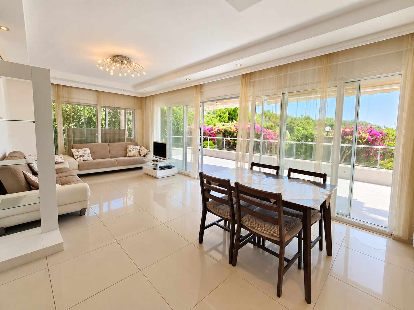 Kitchen-living room with dark wood dining table and panoramic doors in a 2+1 apartment in Turkey