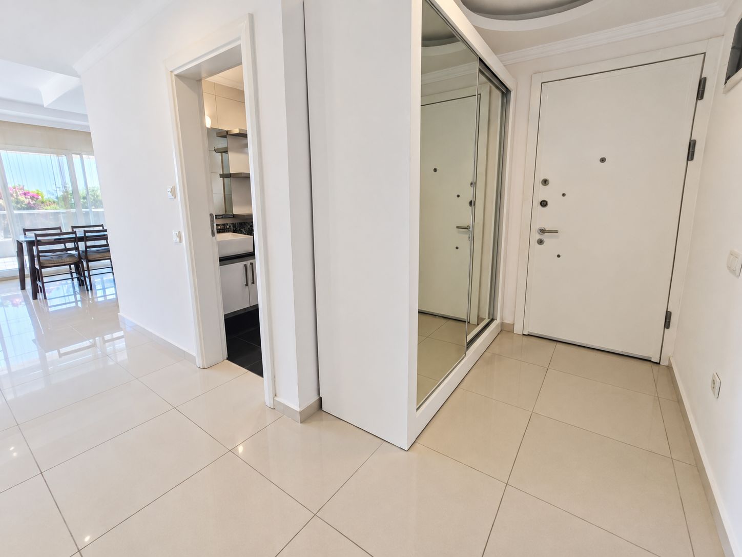 Entry hall with a mirrored built-in wardrobe and white front door in a flat in Konakli