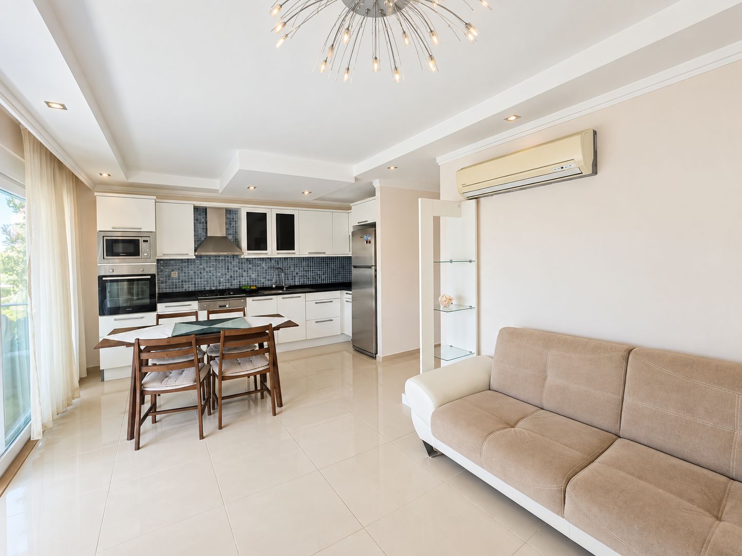 Kitchen-living room with a white suite, blue mosaic backsplash and dark wood dining table