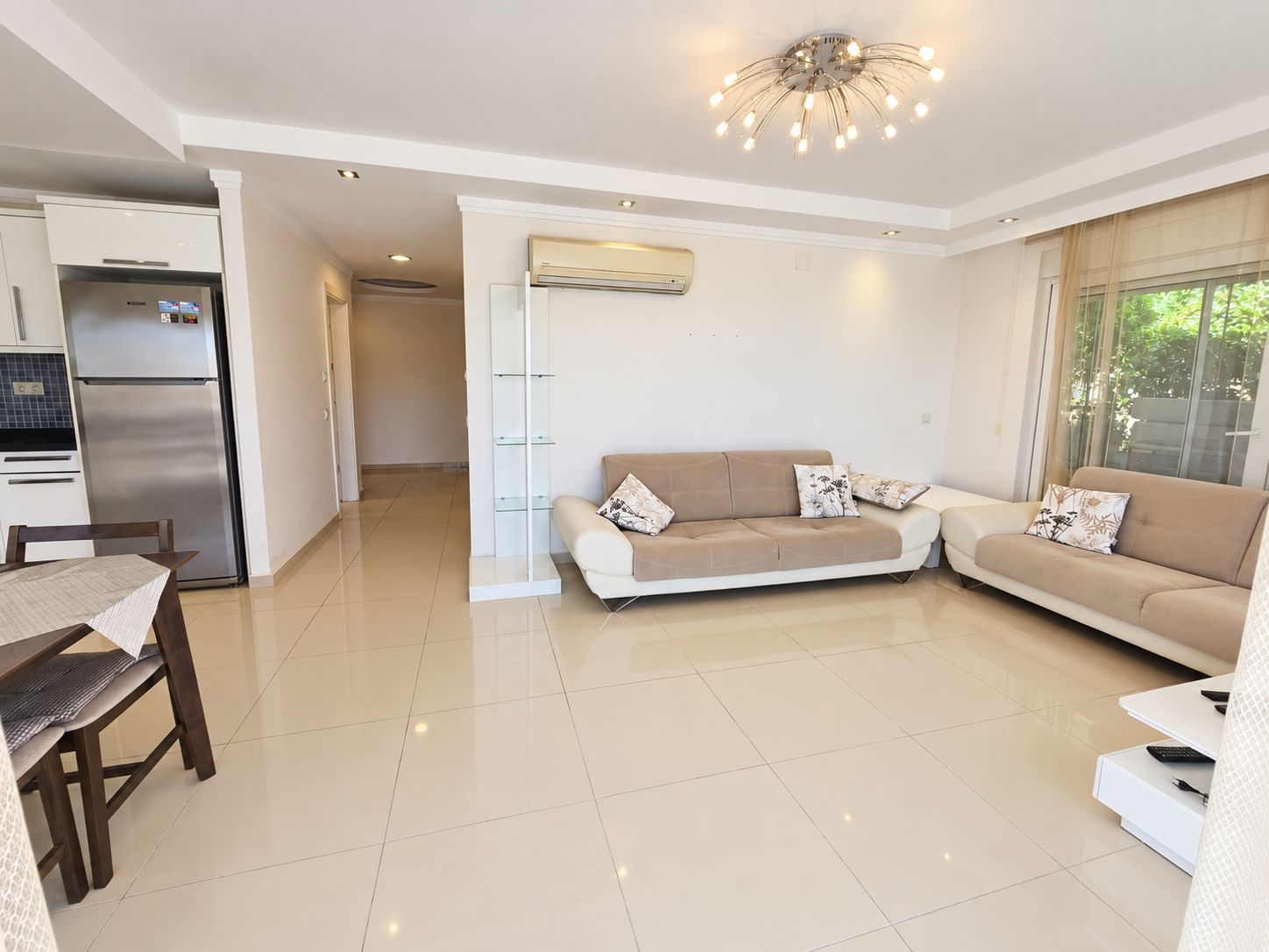Kitchen-living room with two beige sofas and panoramic window in a 2+1 apartment for sale in Alanya