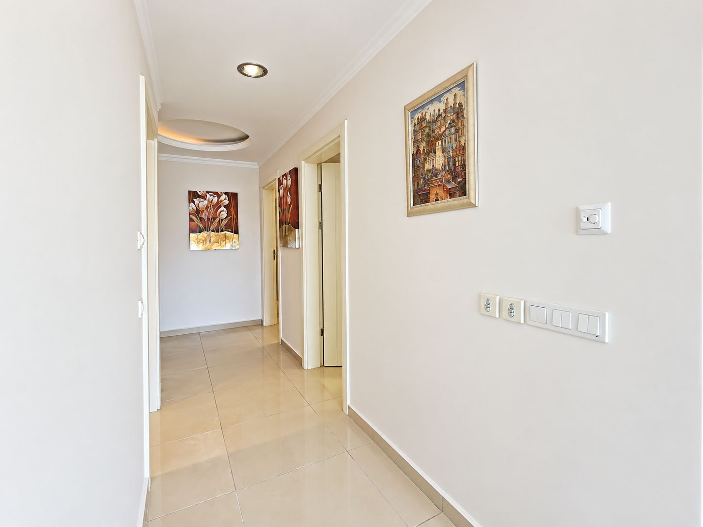 Light corridor with white interior doors, wall art and a lit ceiling recess
