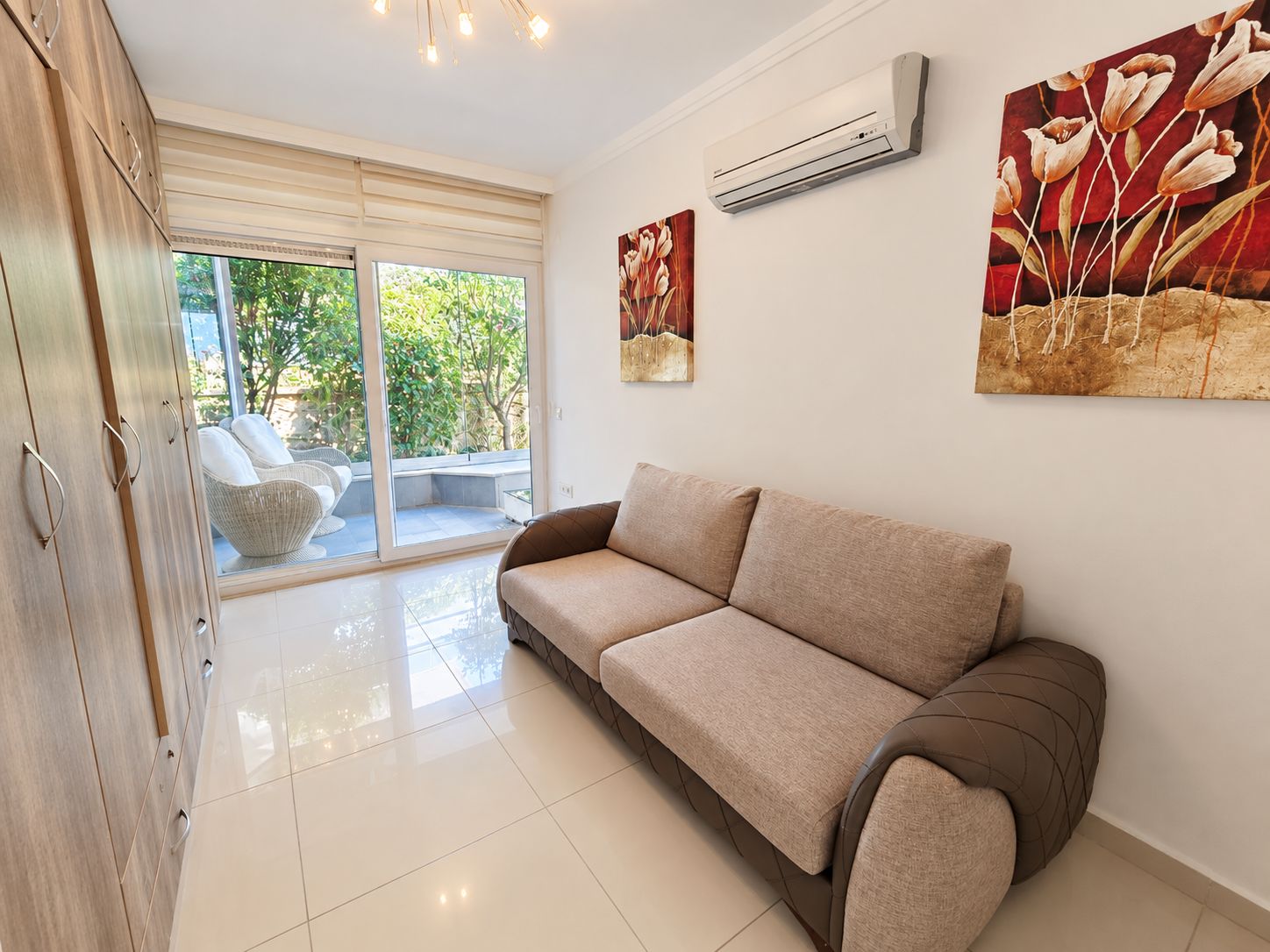 Living room with wooden built-in wardrobe and terrace doors with wicker chairs in Alanya
