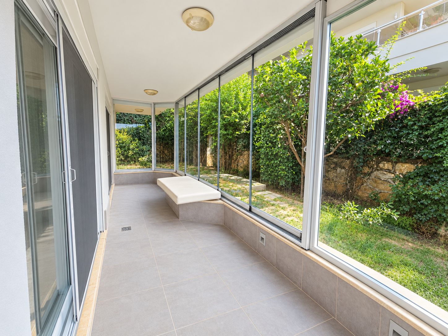 Glazed terrace with a built-in bench and panoramic sliding windows at an apartment for sale