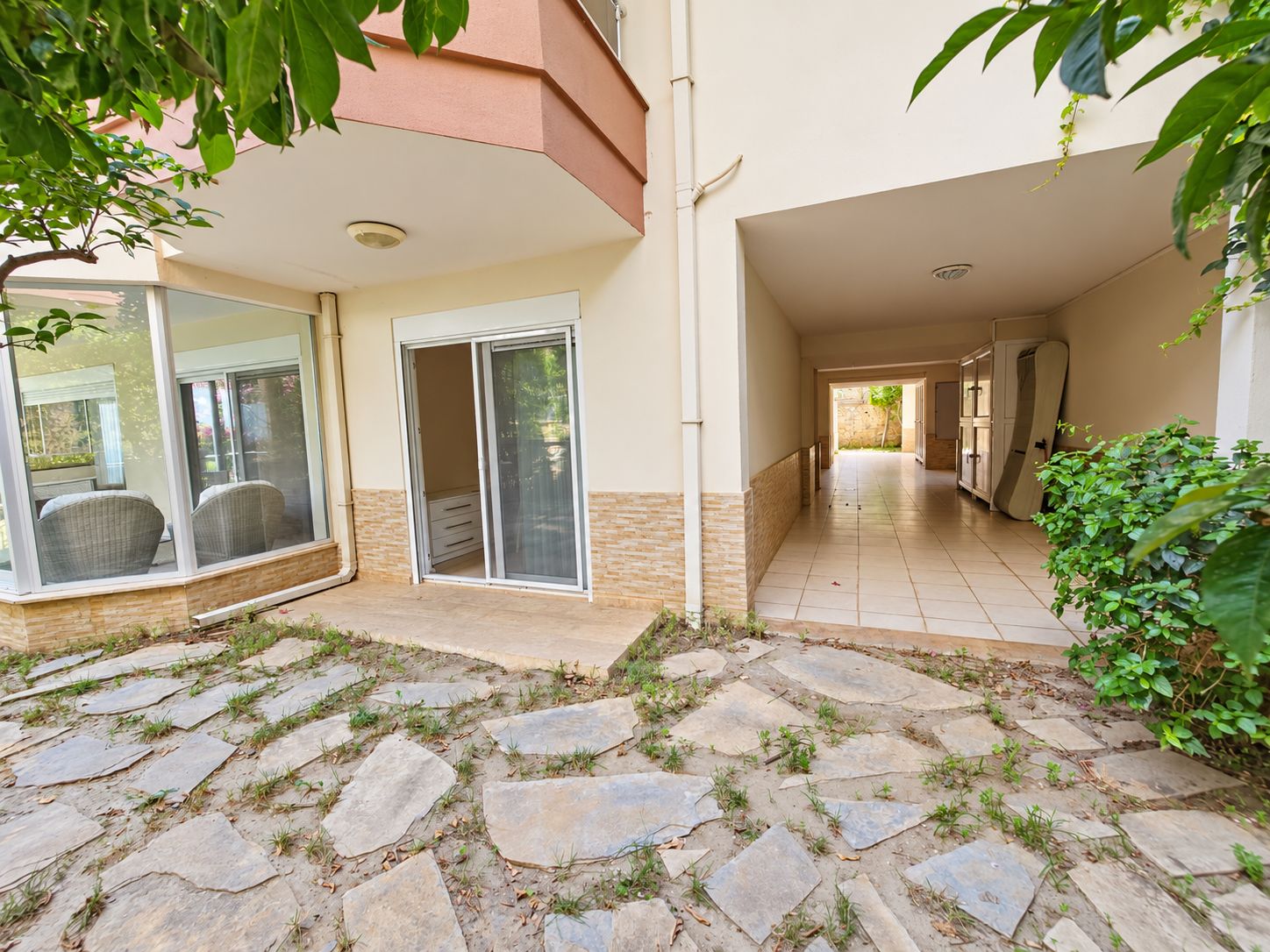 Ground-floor facade with a glazed terrace corner window, stone base and covered walkway