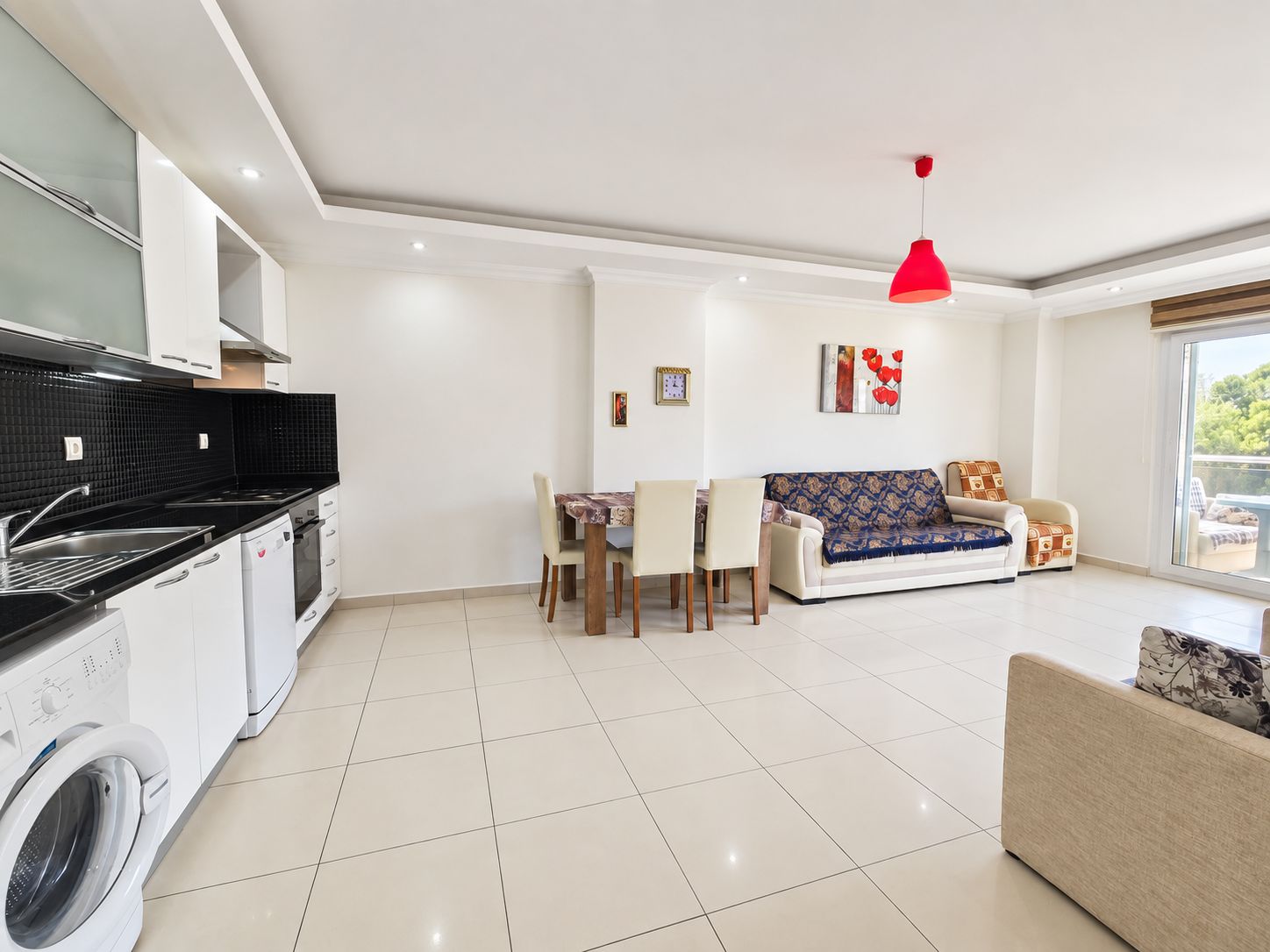 Кухня-гостиная квартиры 1+1 в продаже в Оба с белой кухней и дверью на балкон