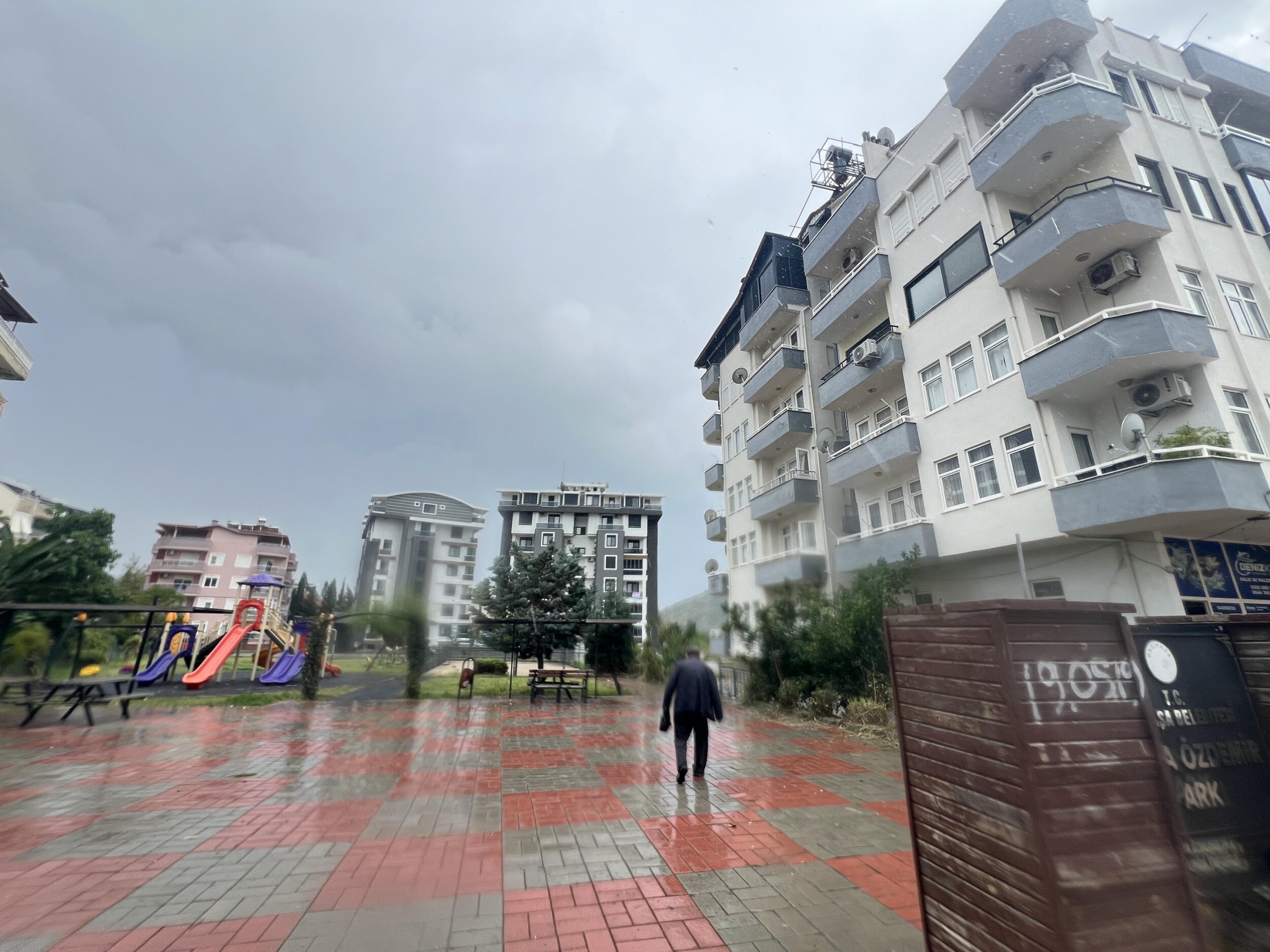Детская площадка с горками и мокрой плиткой во дворе жилого дома в Алании, Турция