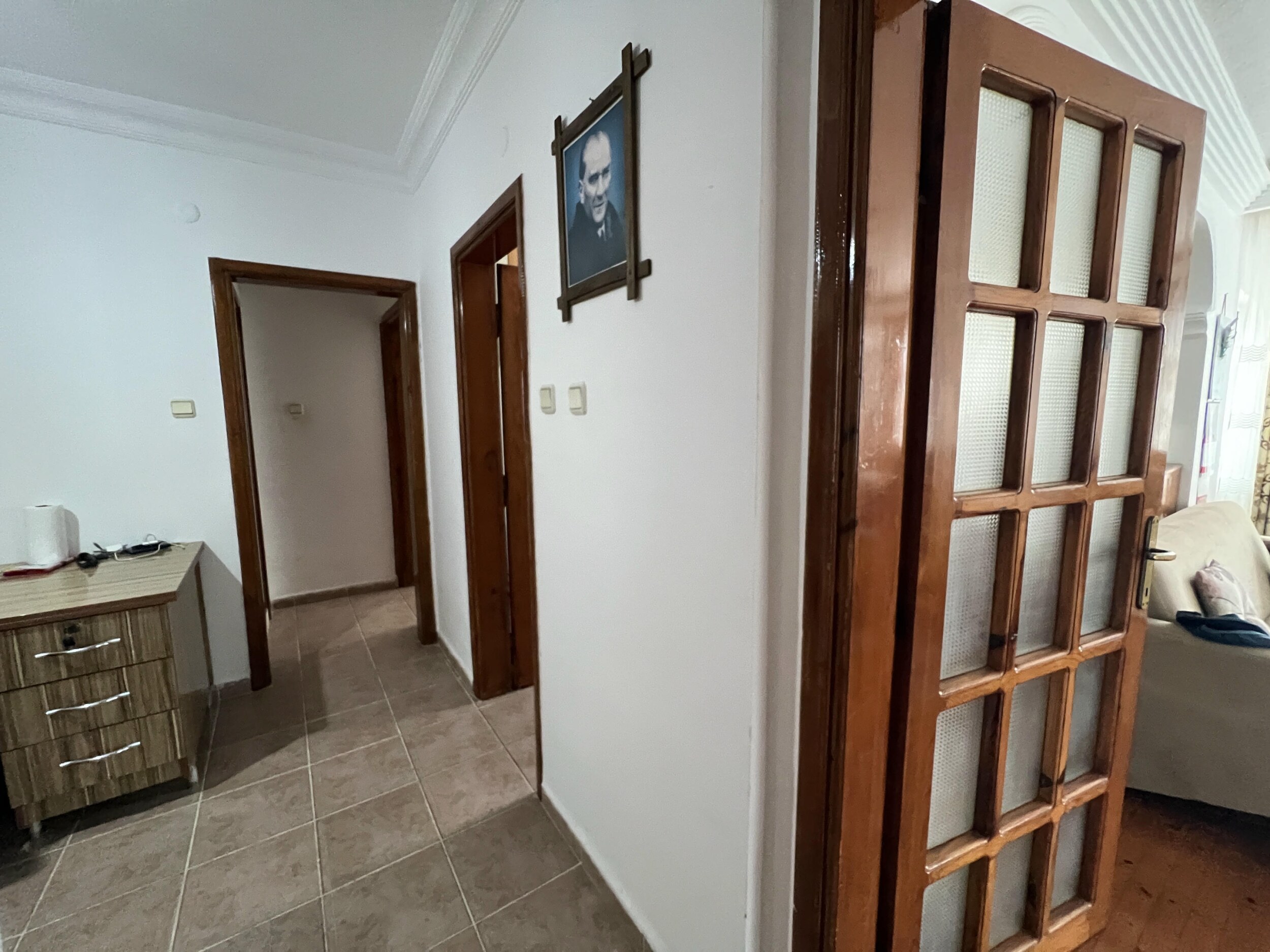 Коридор с серой плиткой, комодом и дверью со вставками из матового стекла