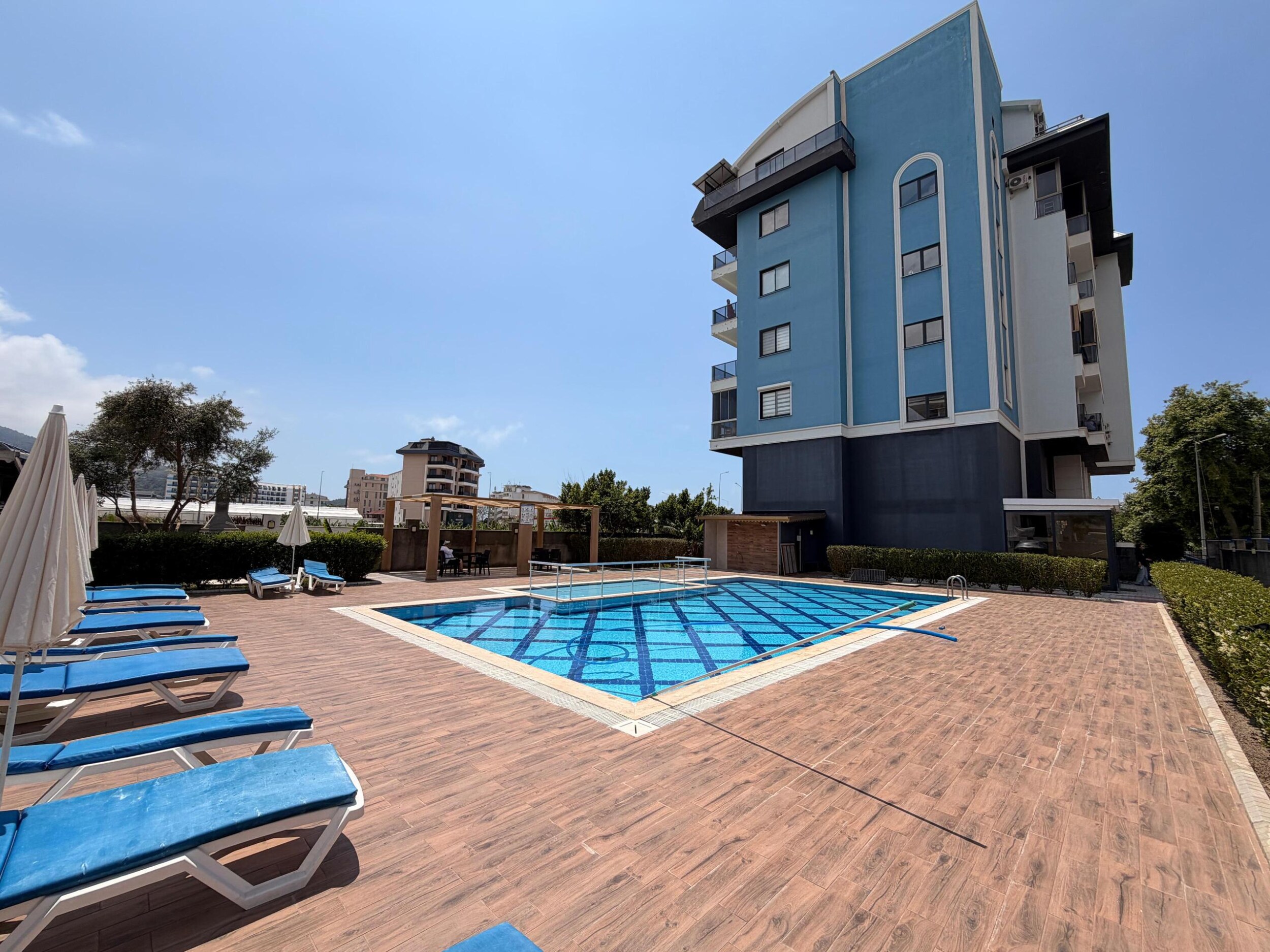 Mavi desenli açık havuz ve şezlonglar, Kargıcak'ta Türkiye'deki daireli sitede