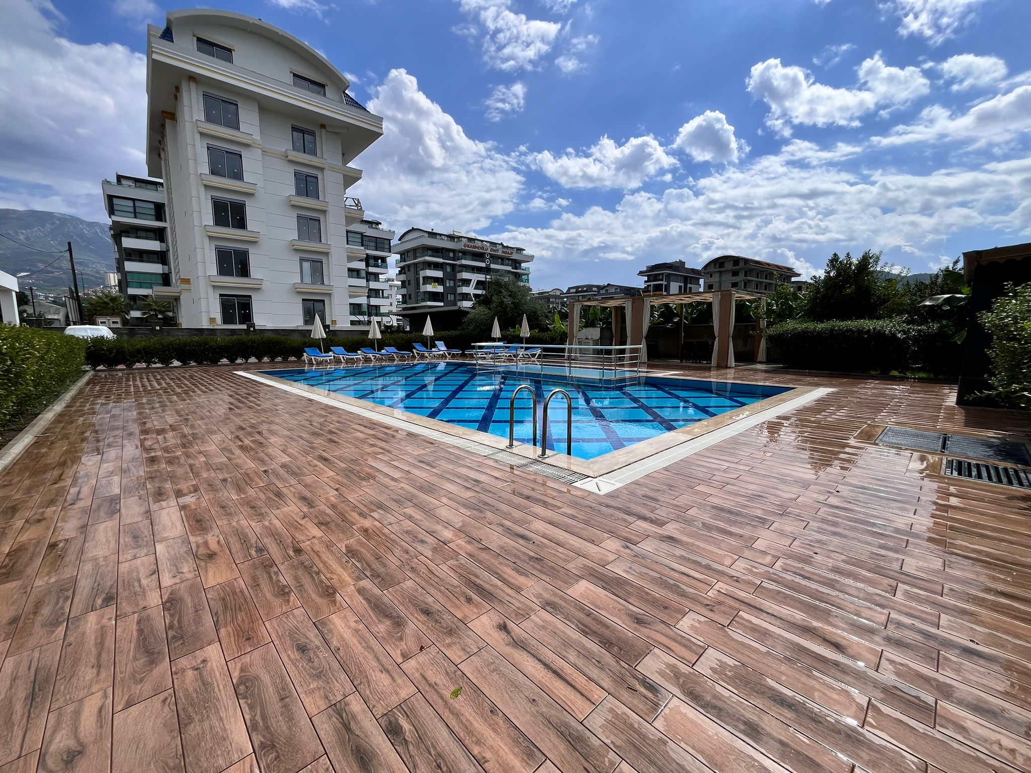 Islak ahşap teraslı havuzun arkasında dağlar, Kargıcak'ta Türkiye'deki apartmanların yanında