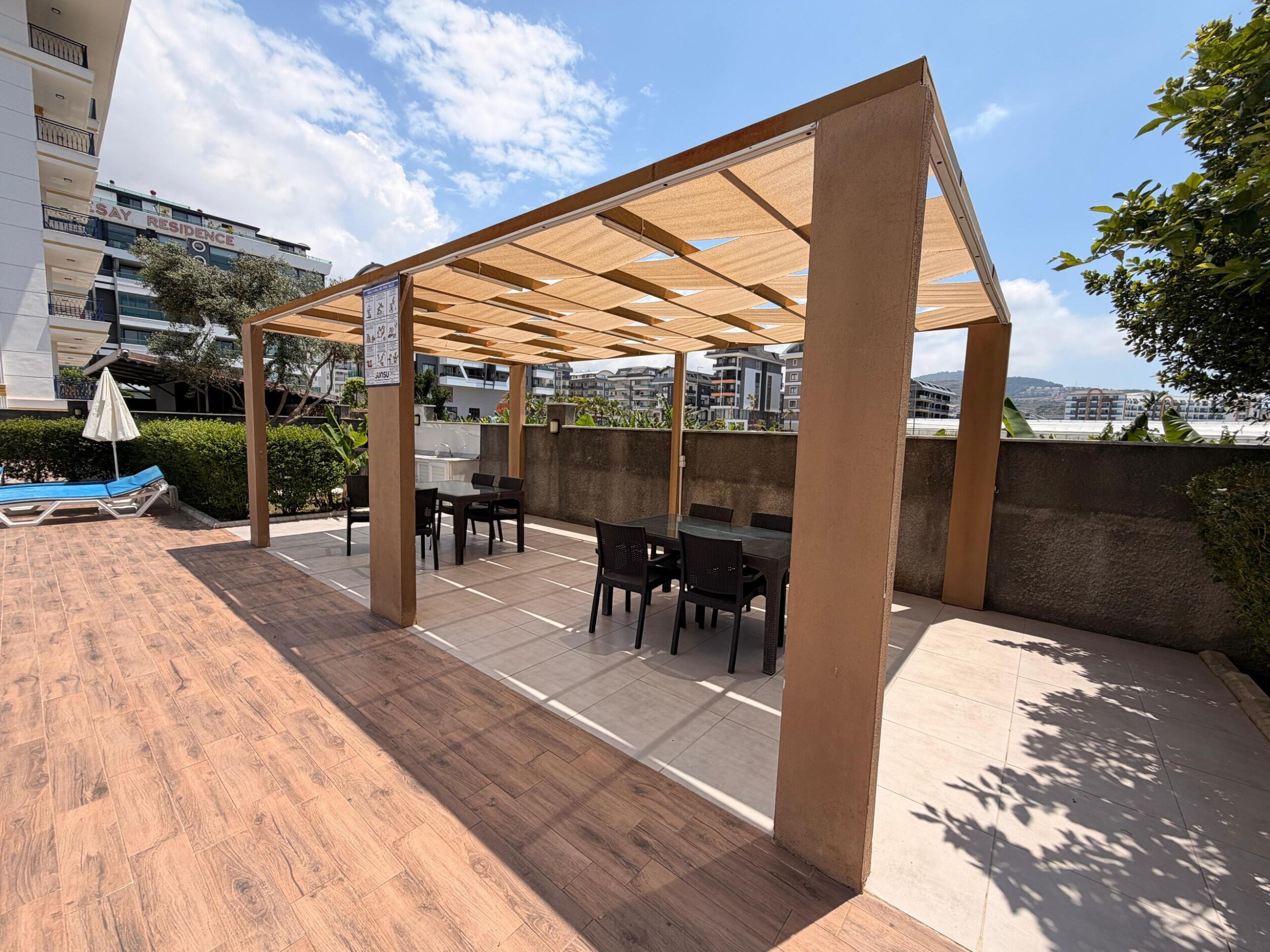 Türkiye'de satılık dairelerin bulunduğu sitede siyah sandalyeli ahşap pergola