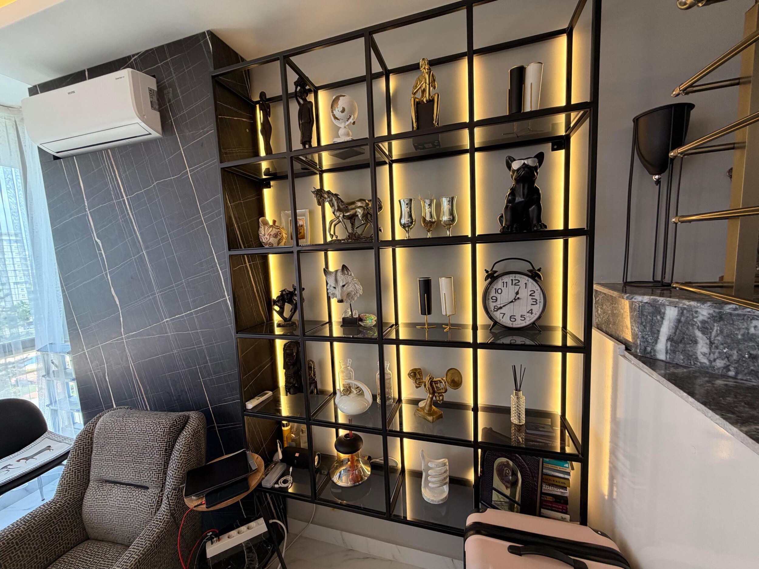 Penthouse salonunda sıcak ışıklı yüksek siyah raf ve koyu mermer vurgu duvarı