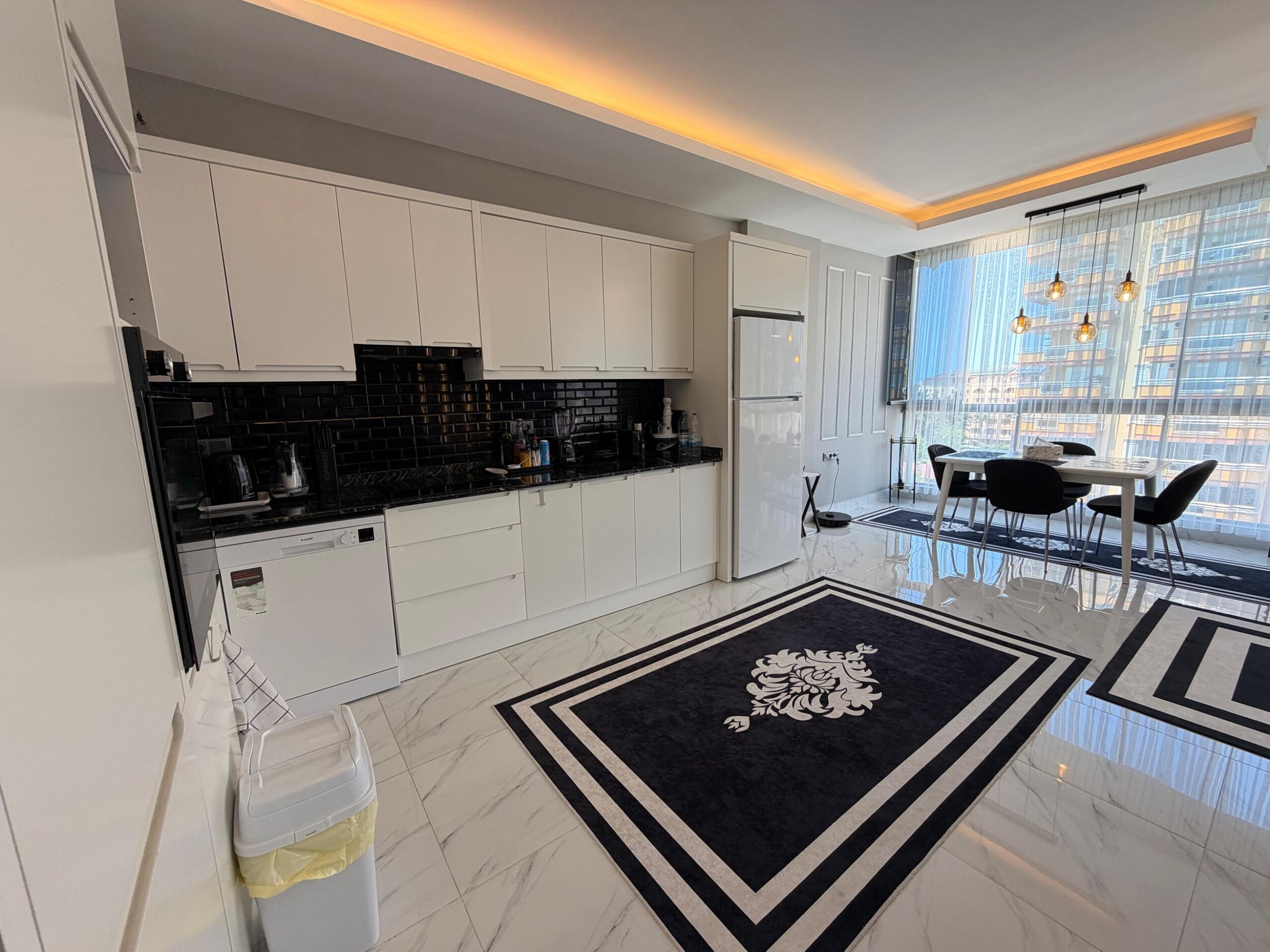 Kargıcak'taki penthouse mutfak-salonda siyah tezgâhlı beyaz dolaplar ve panoramik pencere