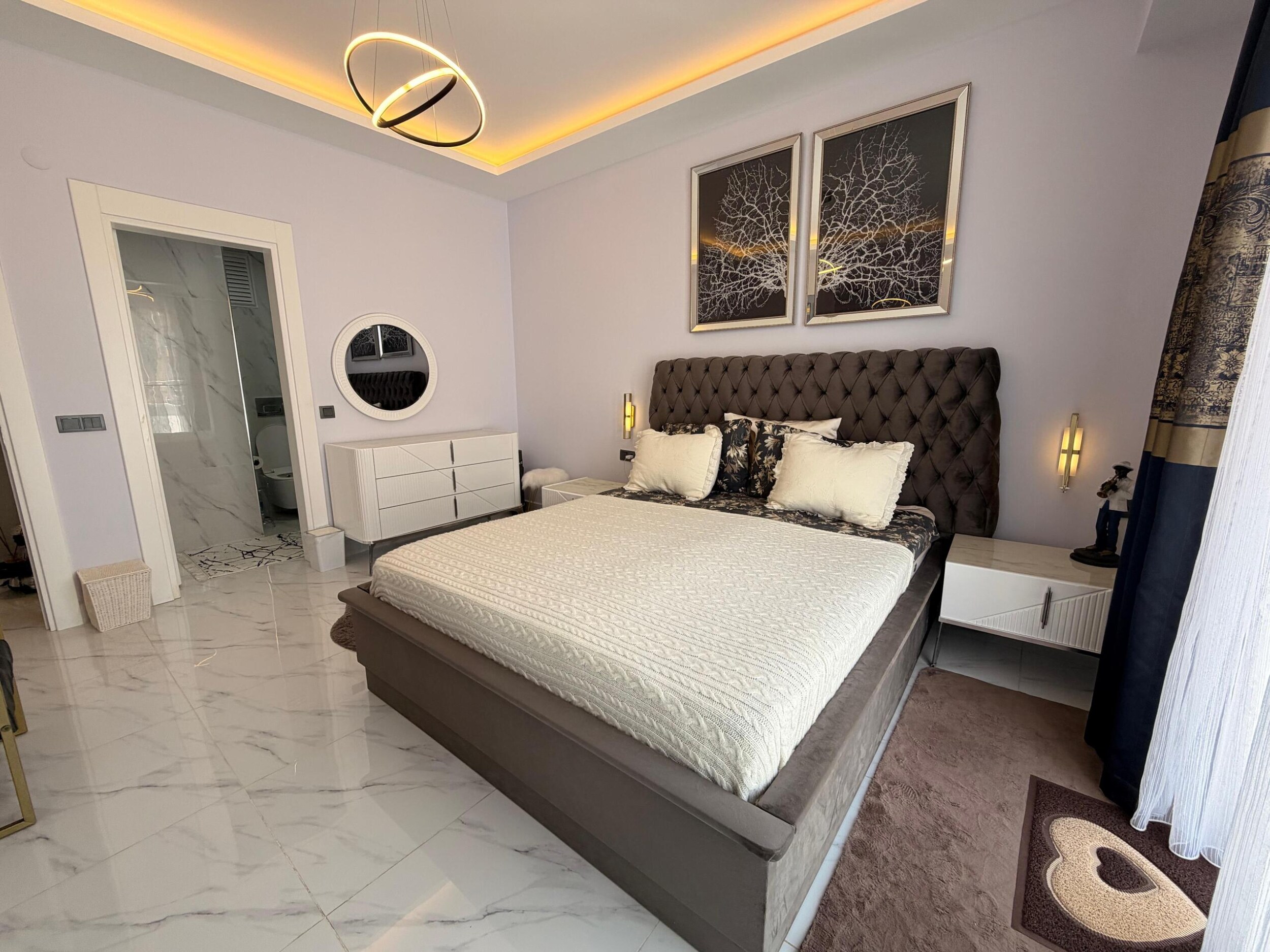 Kargıcak'taki penthouse yatak odasında çift kişilik yatak, beyaz şifonyer ve banyo kapısı