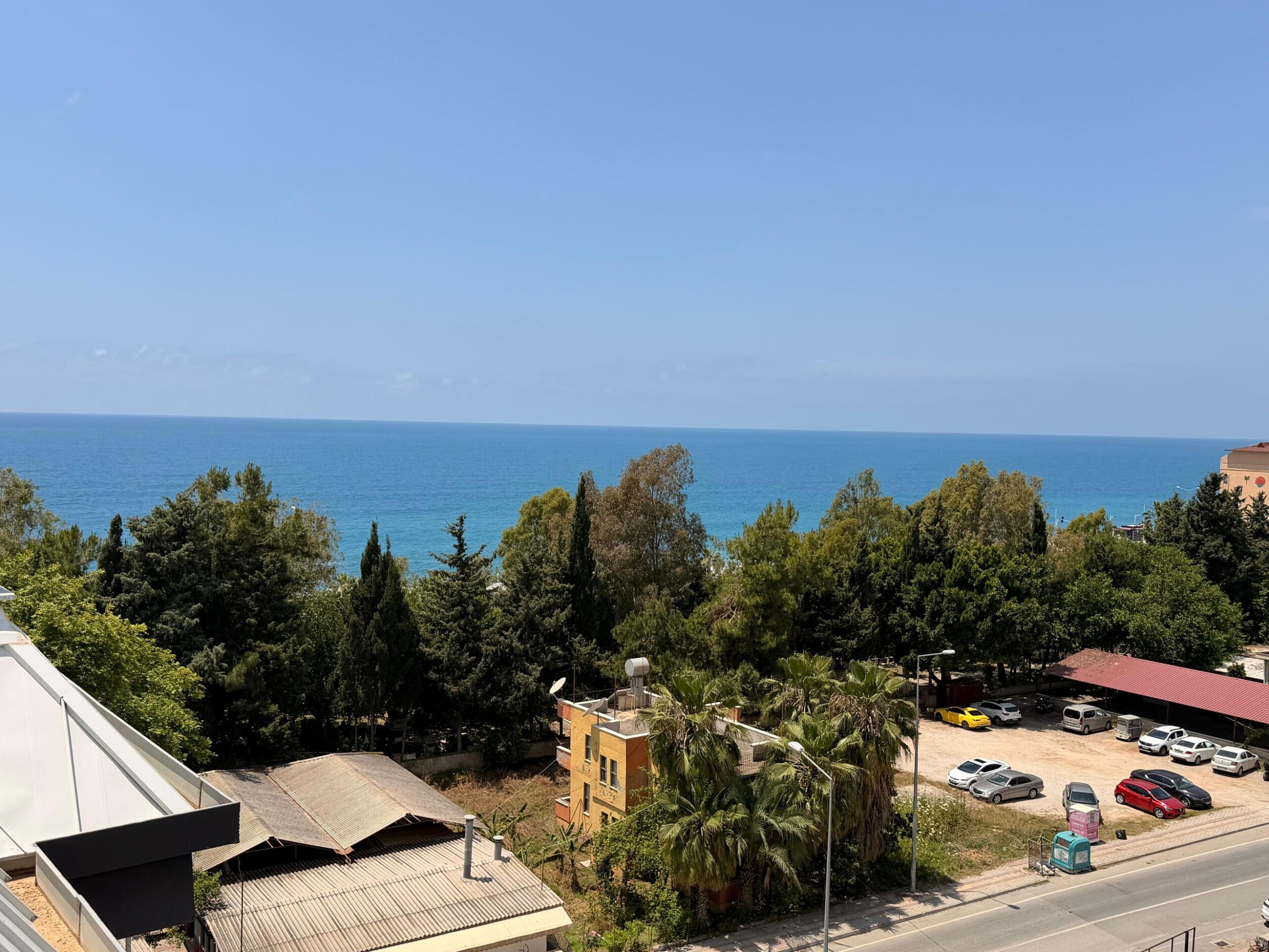 Türkiye'de satılık daire balkonundan deniz, ağaçlar ve aşağıdaki yolun panoramik manzarası