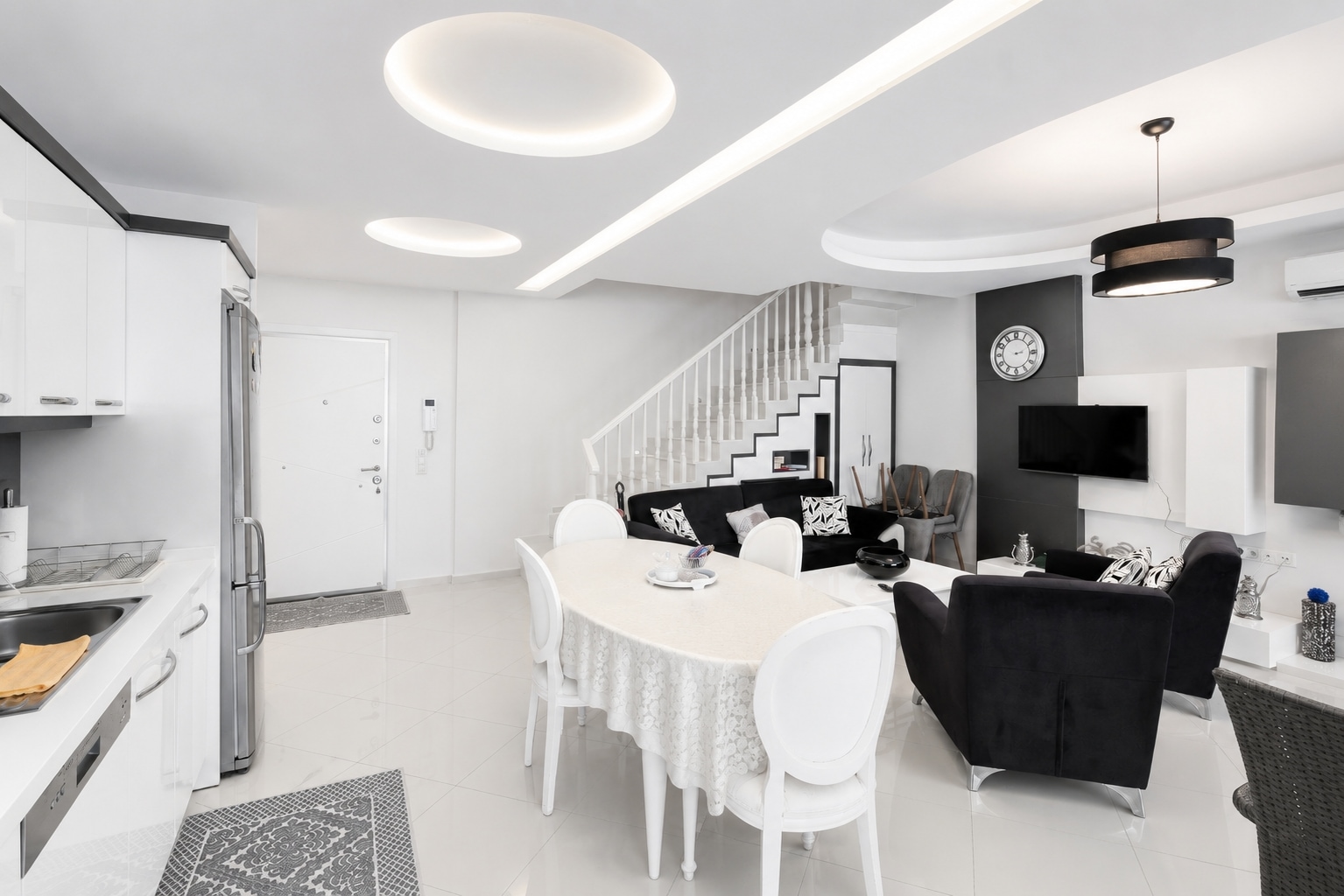 Beyaz mutfak hattı, oval masa ve siyah kanepe bulunan mutfaklı salon, Türkiye’de satılık dublekste
