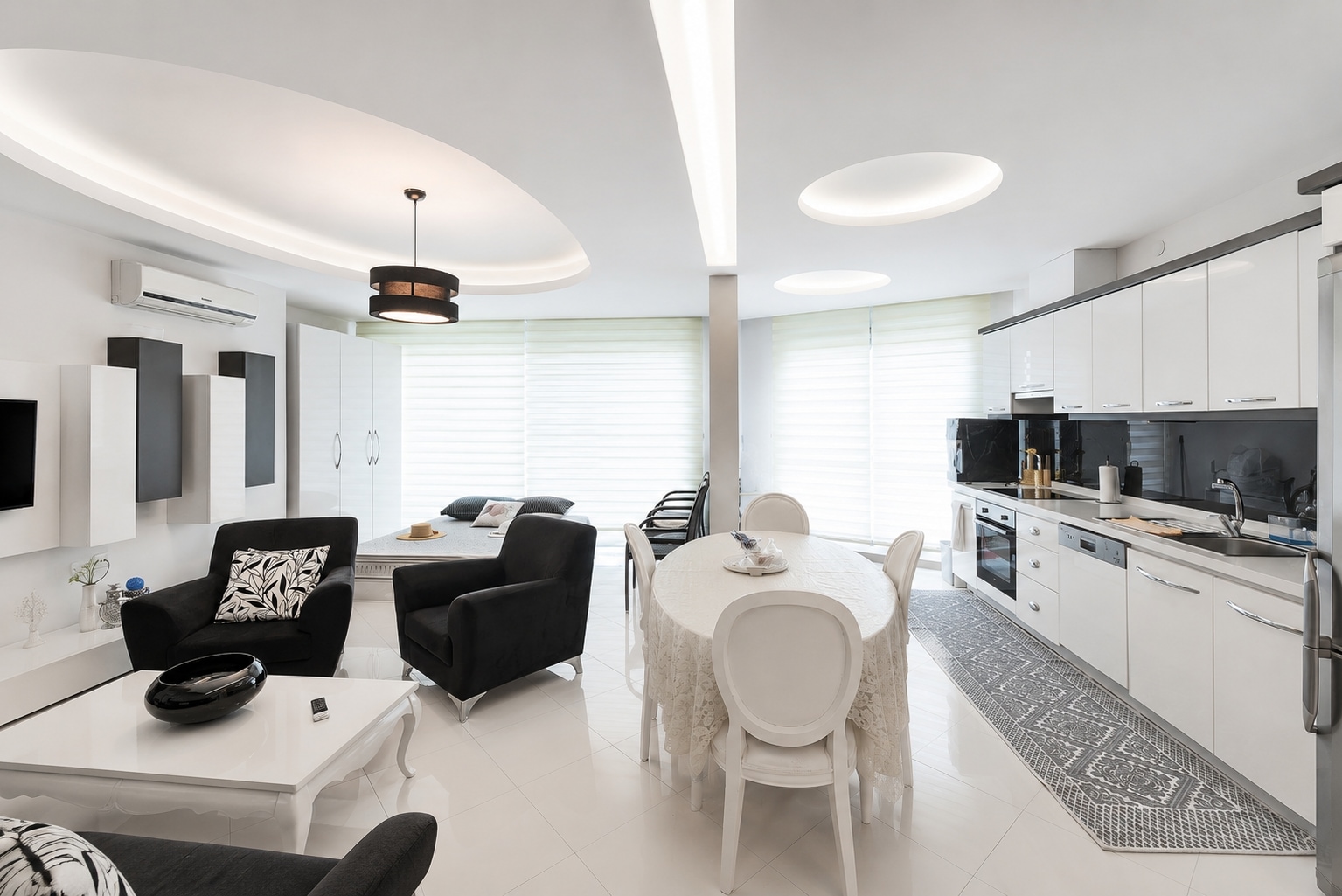 Geniş stor perdeli pencere, beyaz mutfak ve siyah koltuklarla mutfaklı salon, Türkiye’nin Alanya kentinde