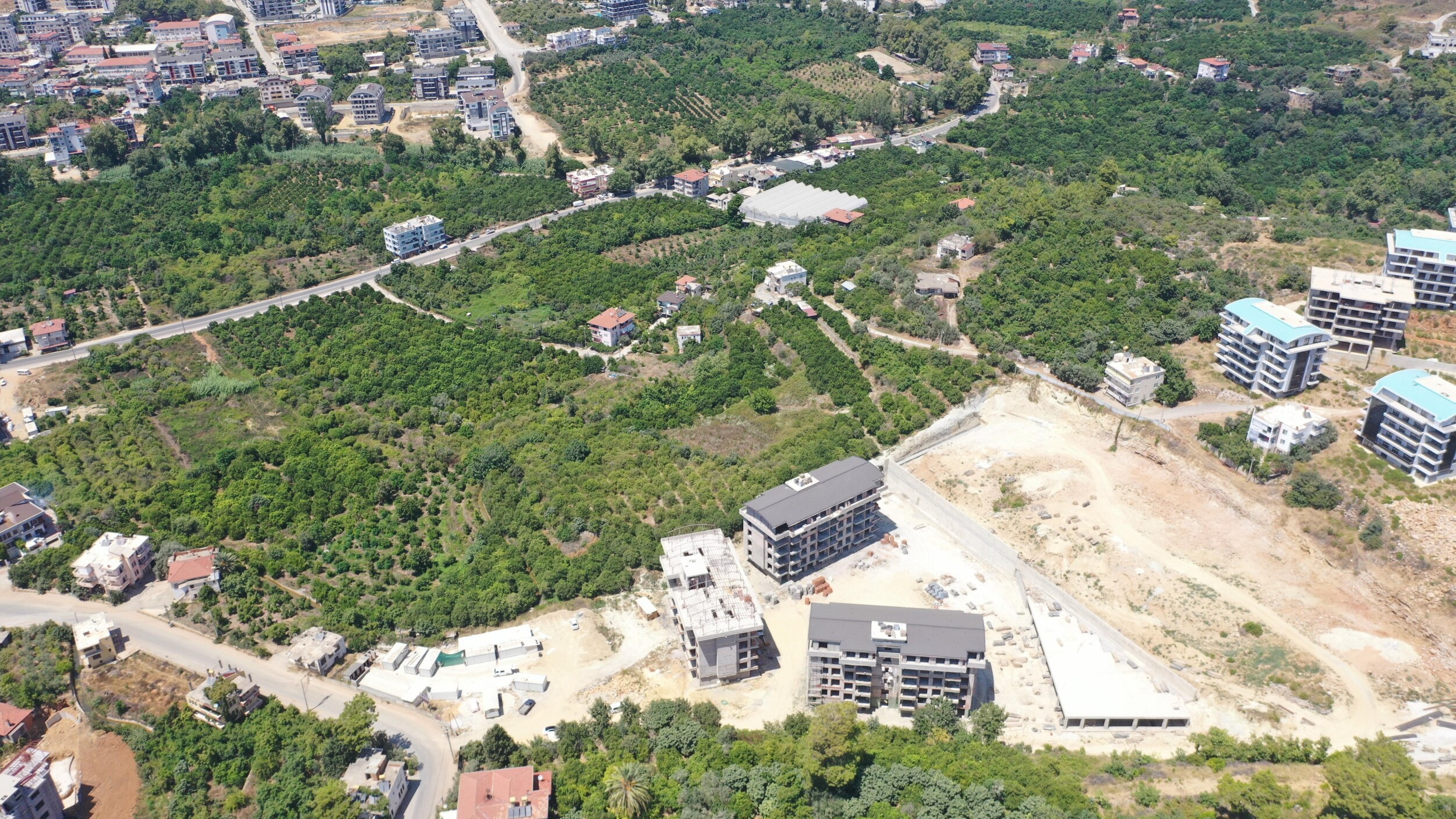 Havadan şantiye alanında yükselen çok katlı bloklar, kıvrımlı yollar ve yeşil bahçeler, Oba’da Türkiye’de
