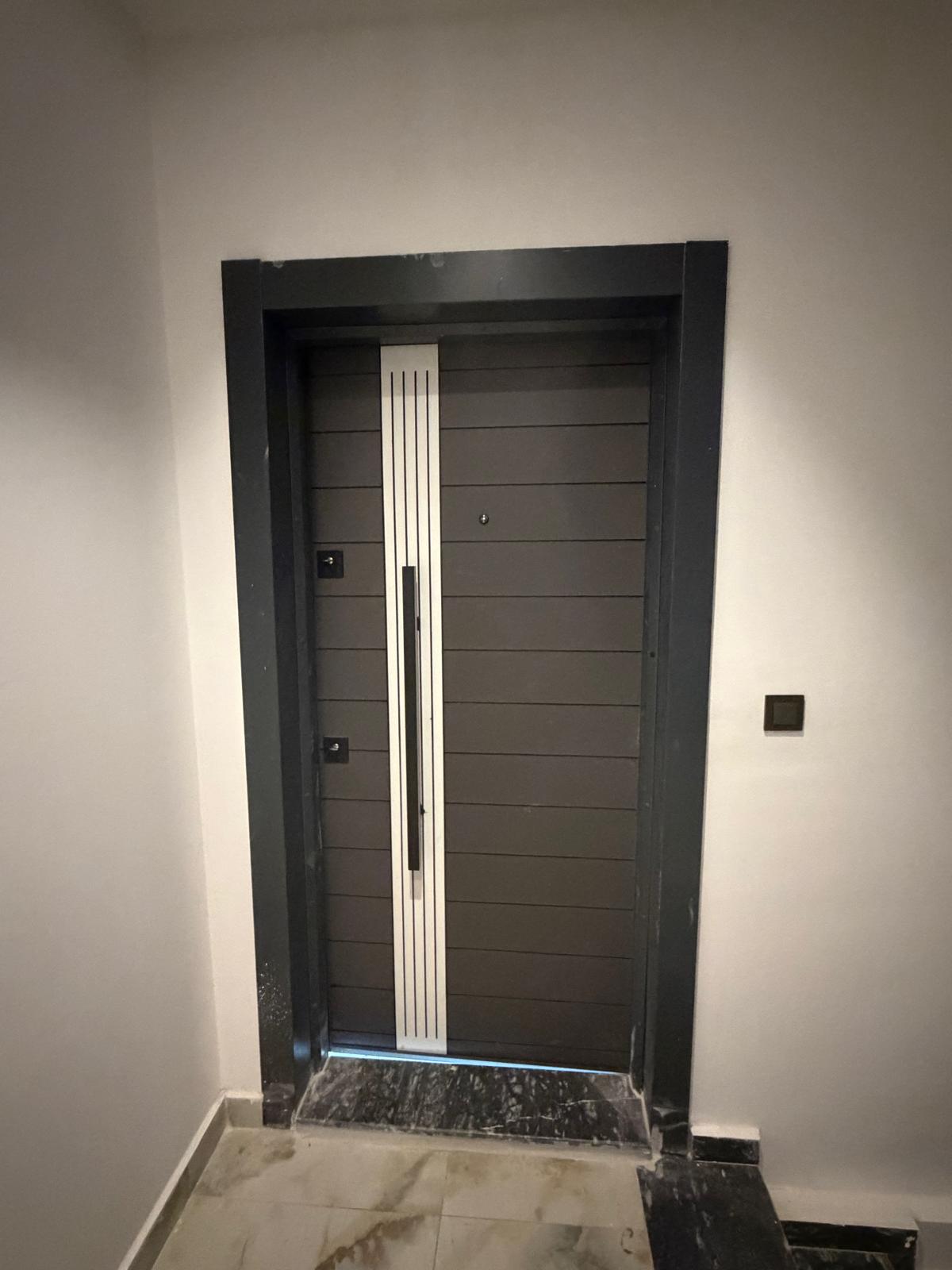 Hallway with a dark entrance door, pale walls and a marble threshold