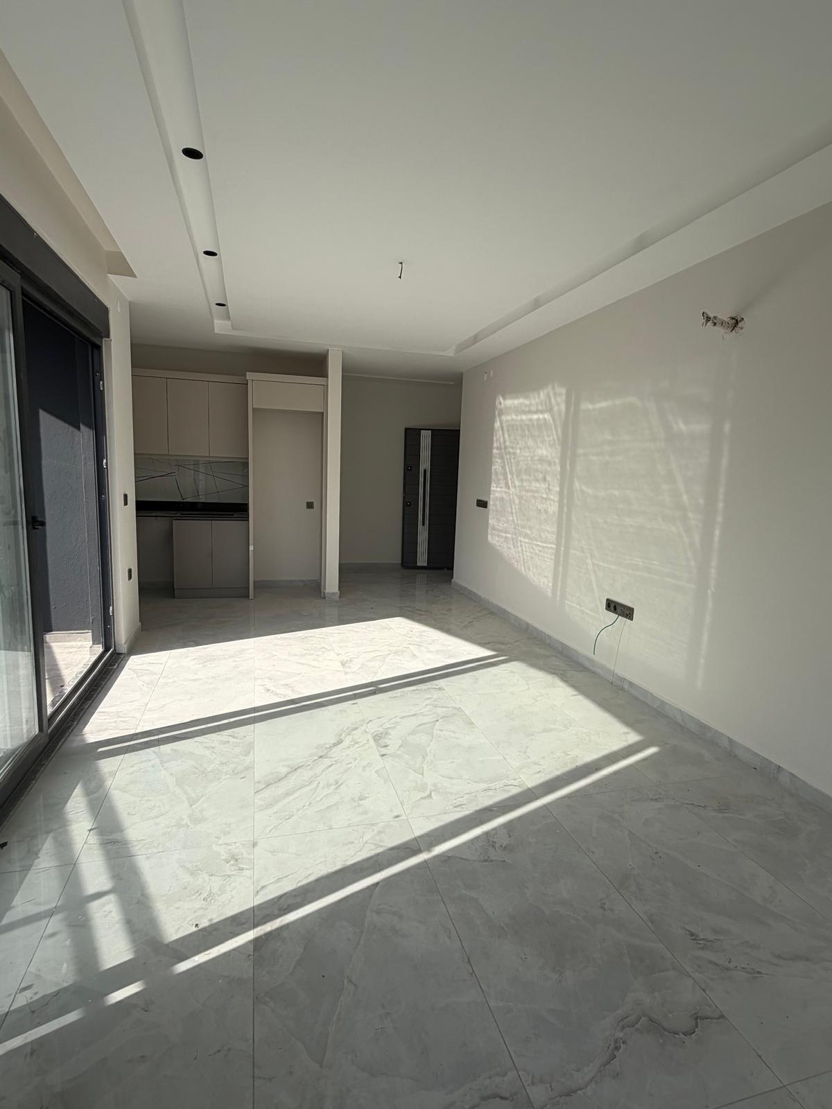 Light fitted kitchen cabinets and a panoramic glass door define the living room in Alanya