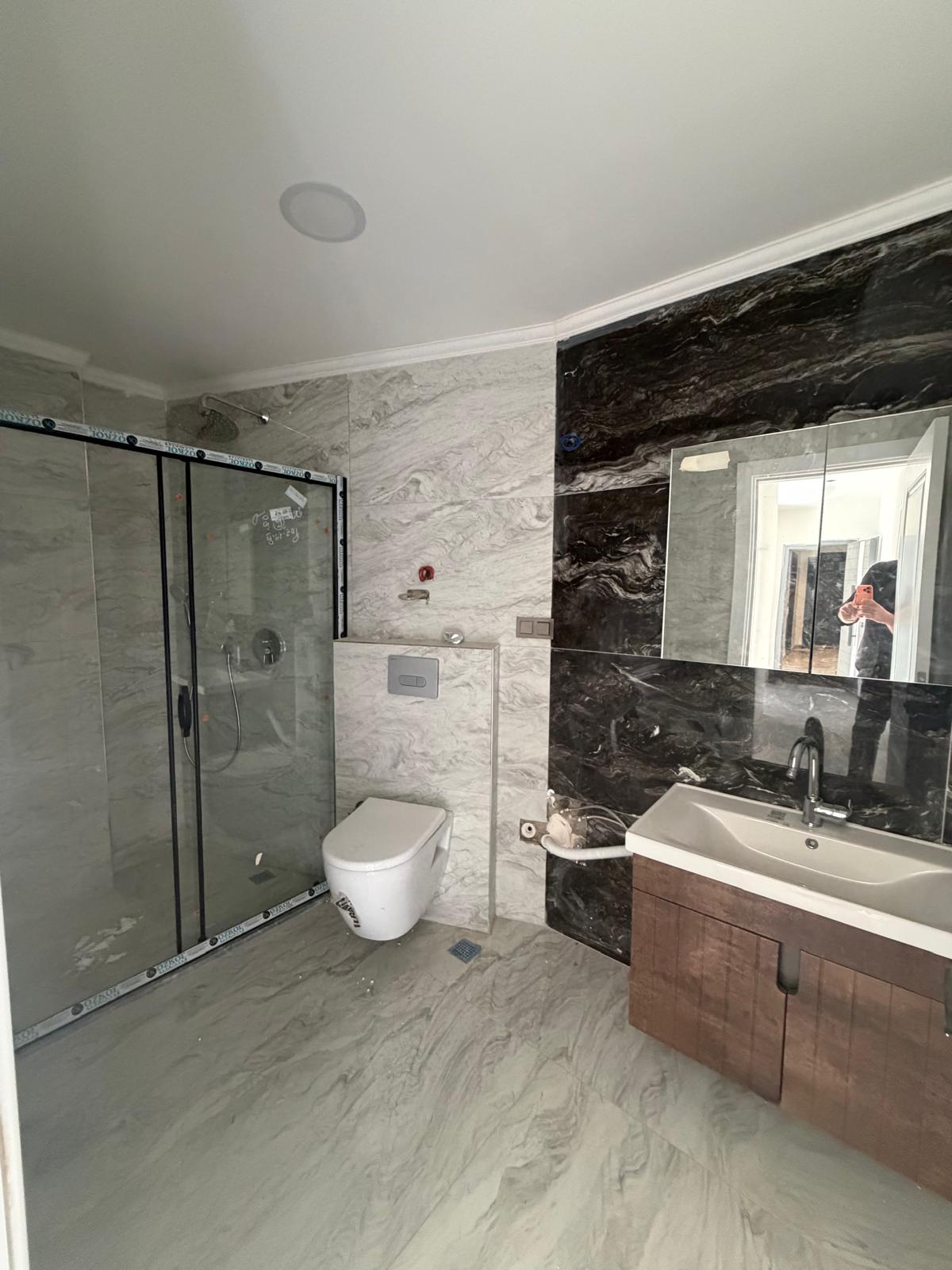 Bathroom with a glass shower enclosure and black marble panel in a home in Alanya