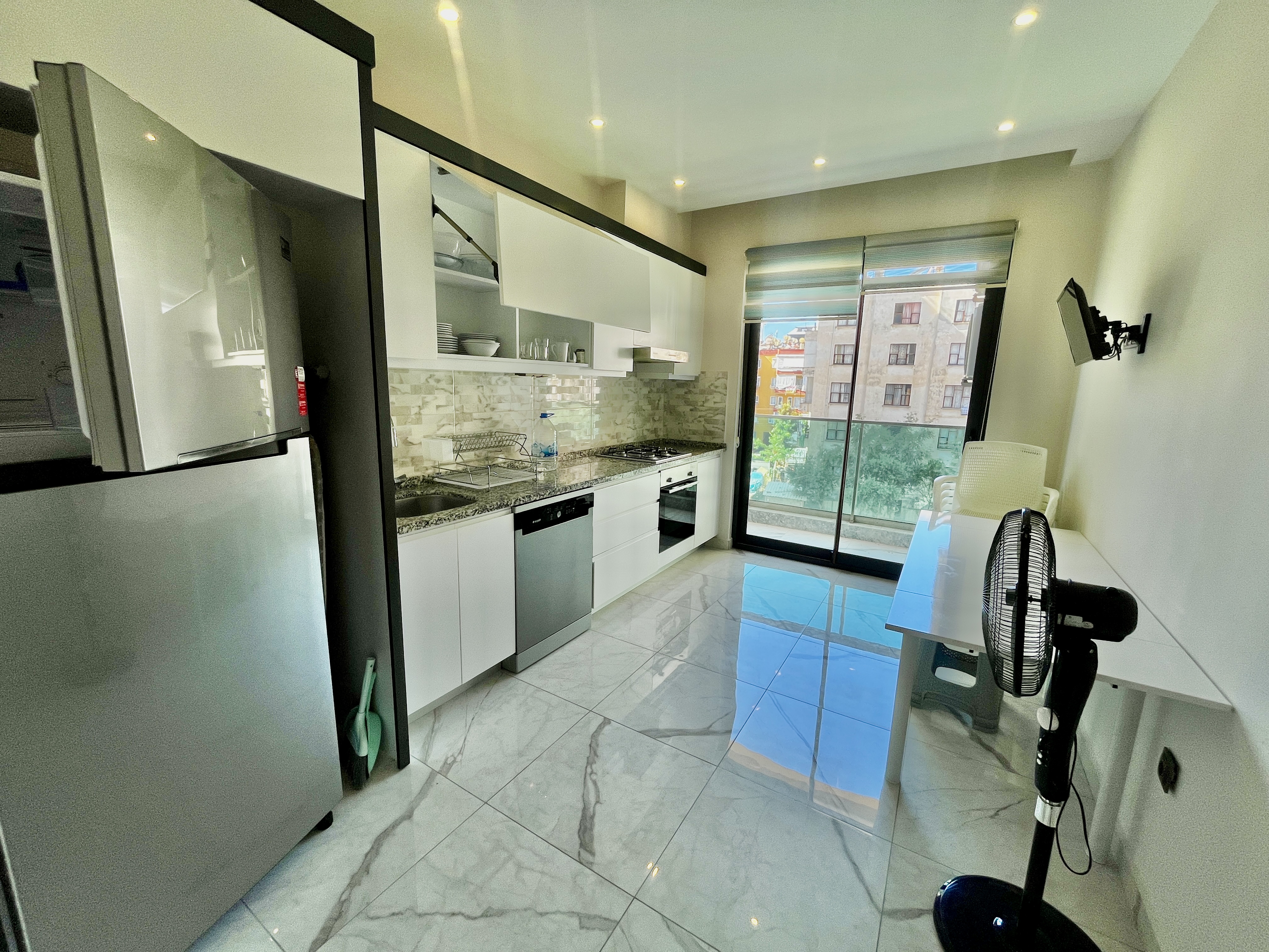 Kitchen with white cabinetry, built-in appliances and a dining table by the window