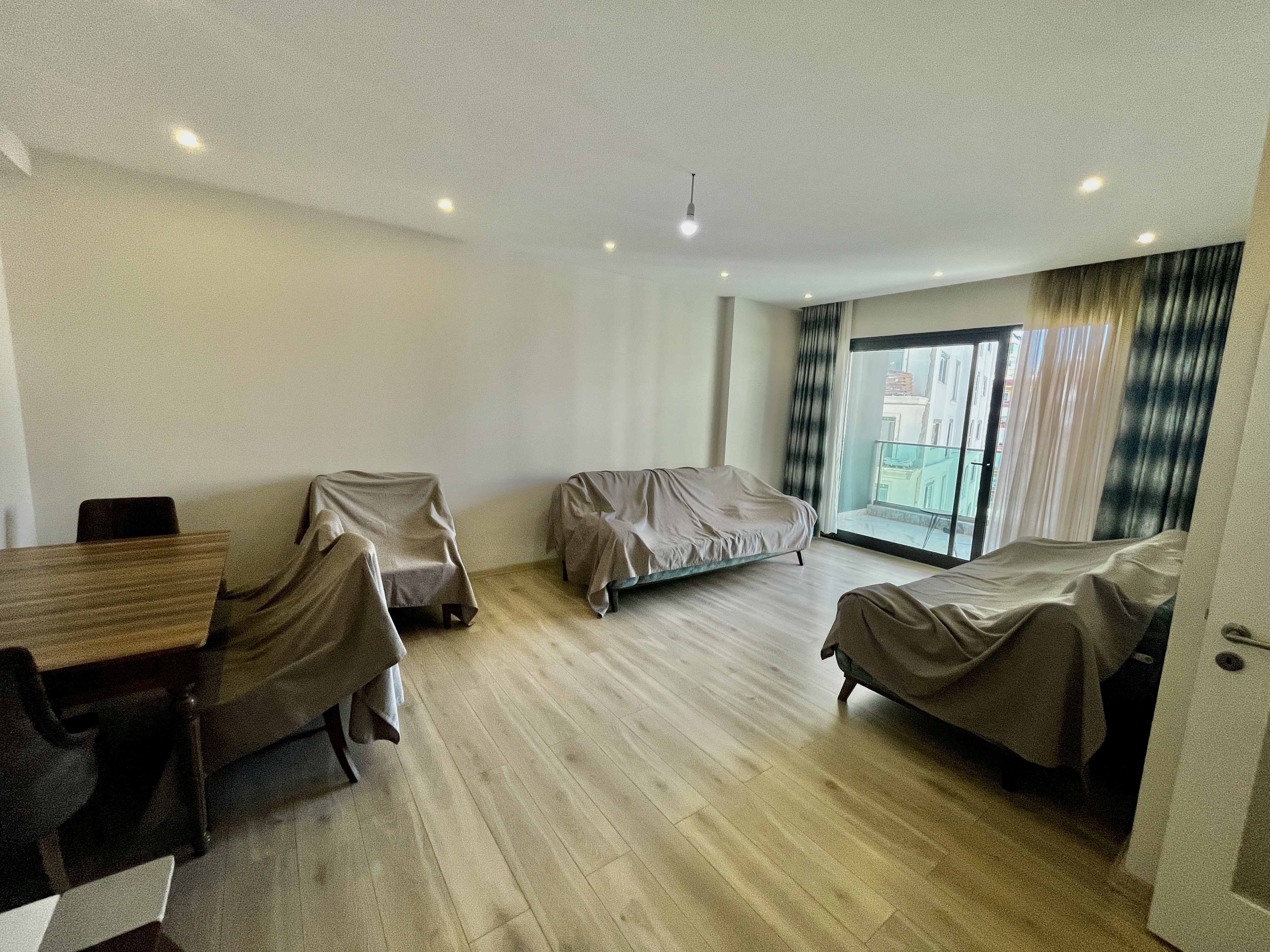 Living room with sofa bed, armchairs and panoramic glazing in an apartment for sale in Alanya