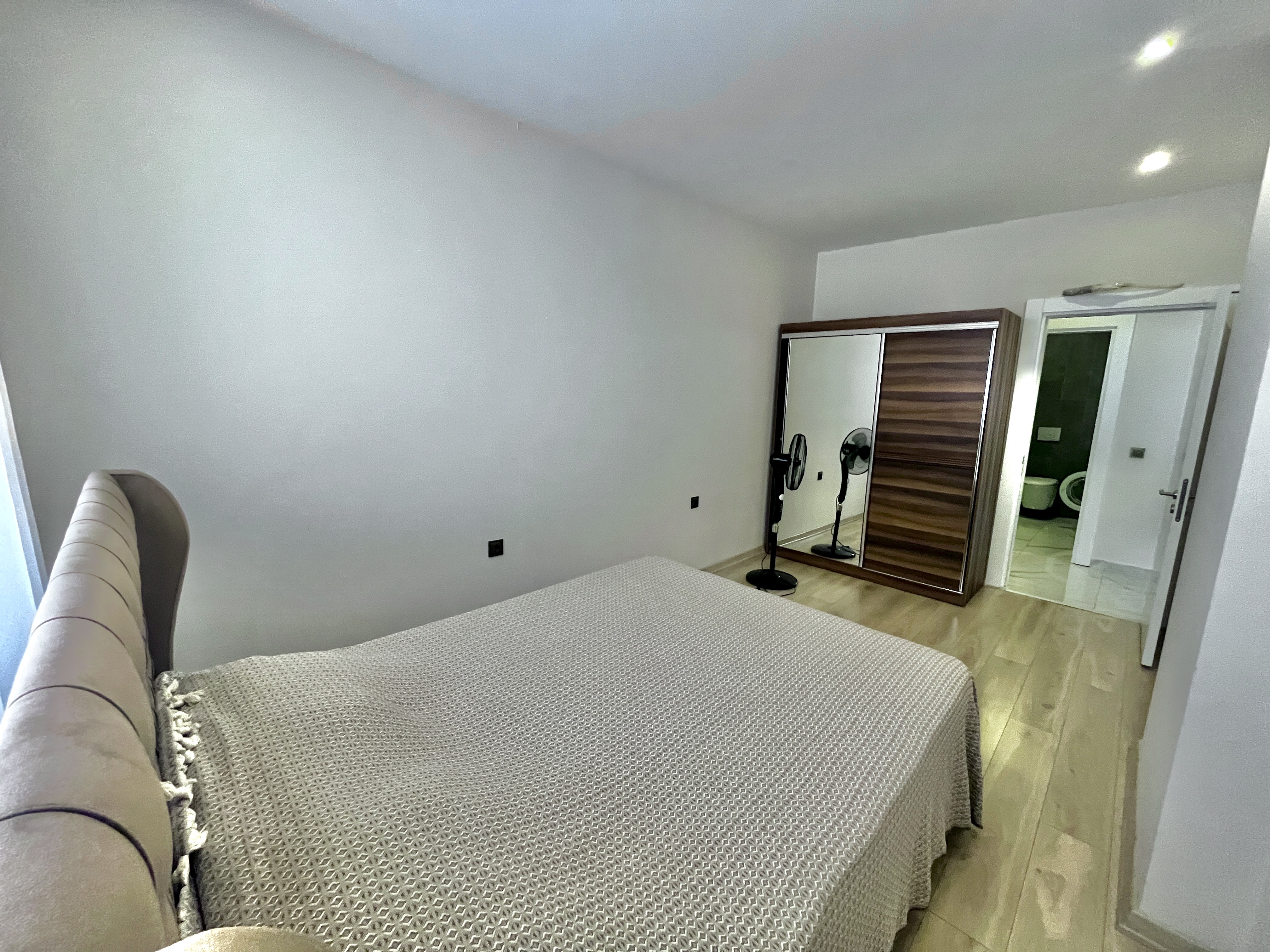 Bedroom with double bed, mirrored wardrobe and bathroom door in an apartment