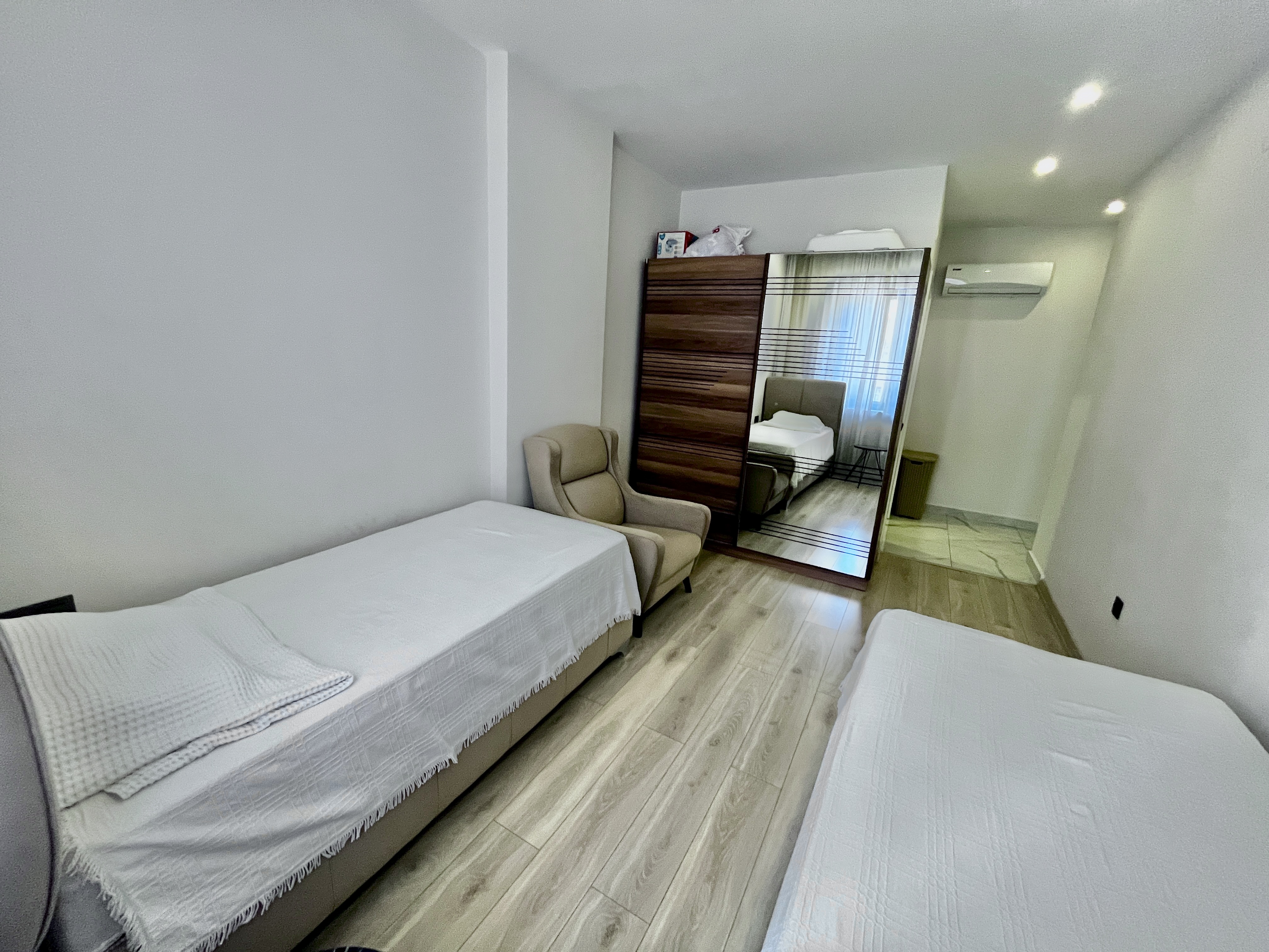 Bedroom with two single beds, mirrored wardrobe and two armchairs by the window