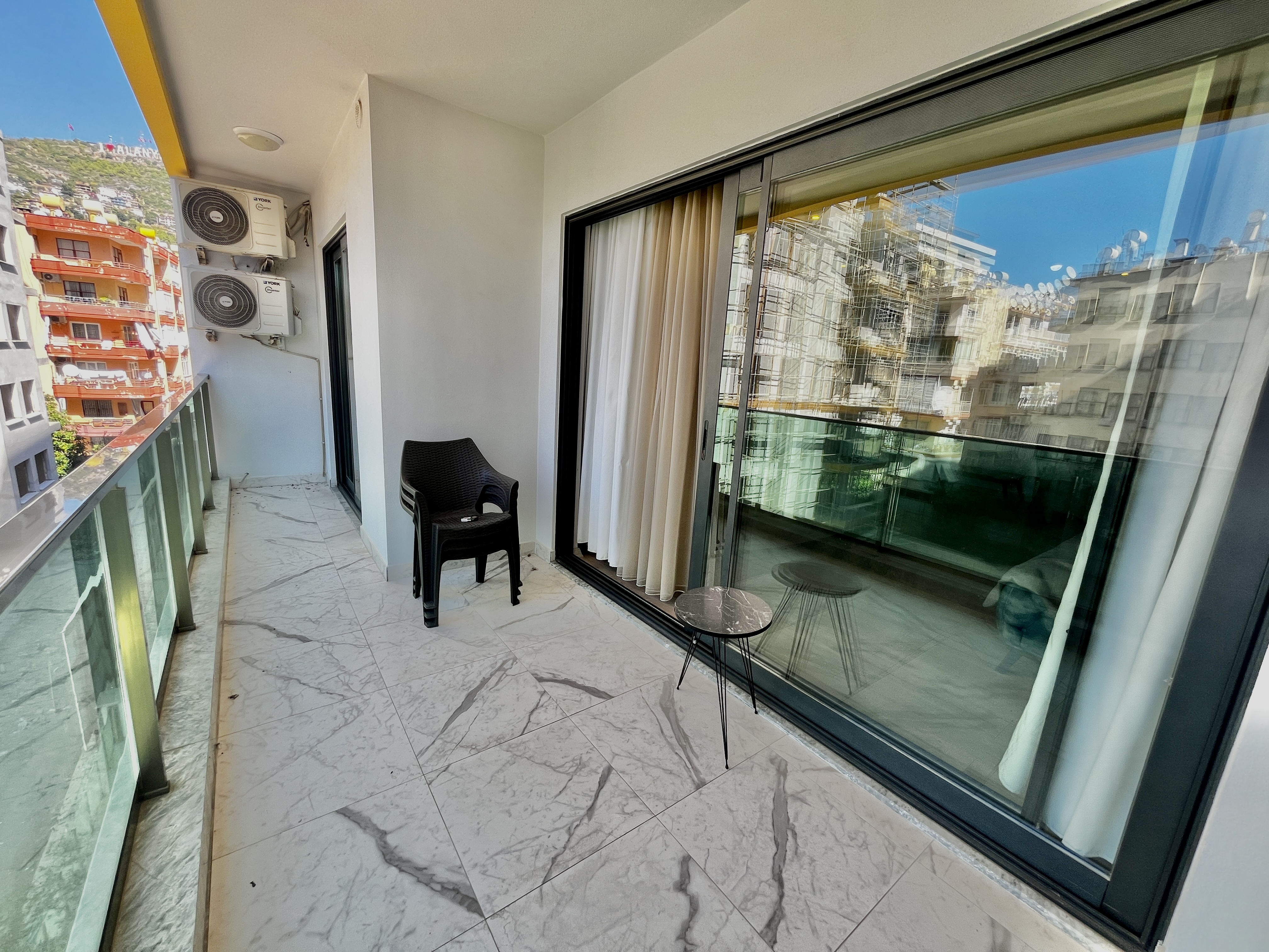 Balcony with marble tile, glass railing and panoramic glazing in Alanya, Turkey