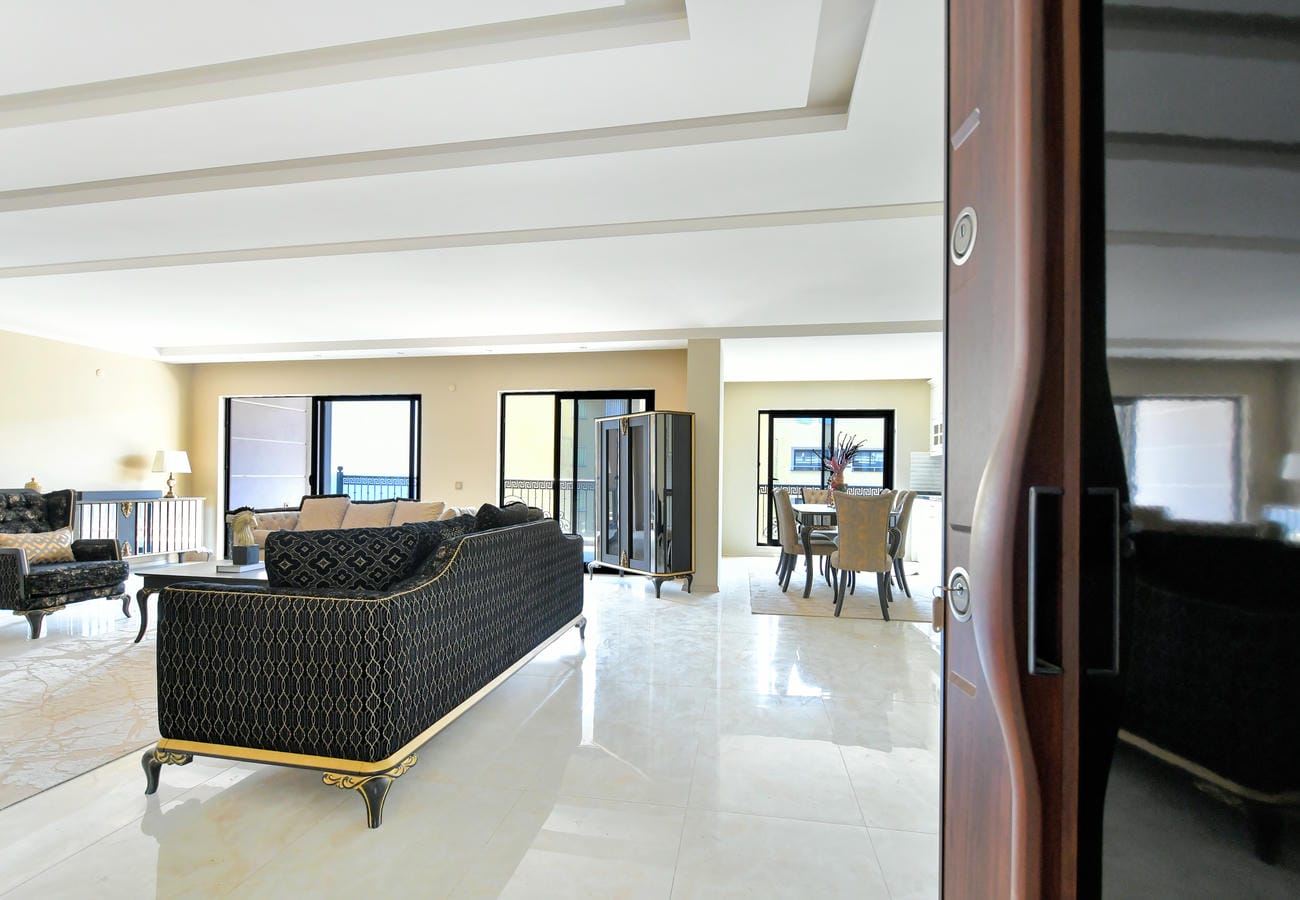 Kargıcak’ta penthouse’un mutfaklı salonunda siyah ve açık renk kanepelerle yemek masası