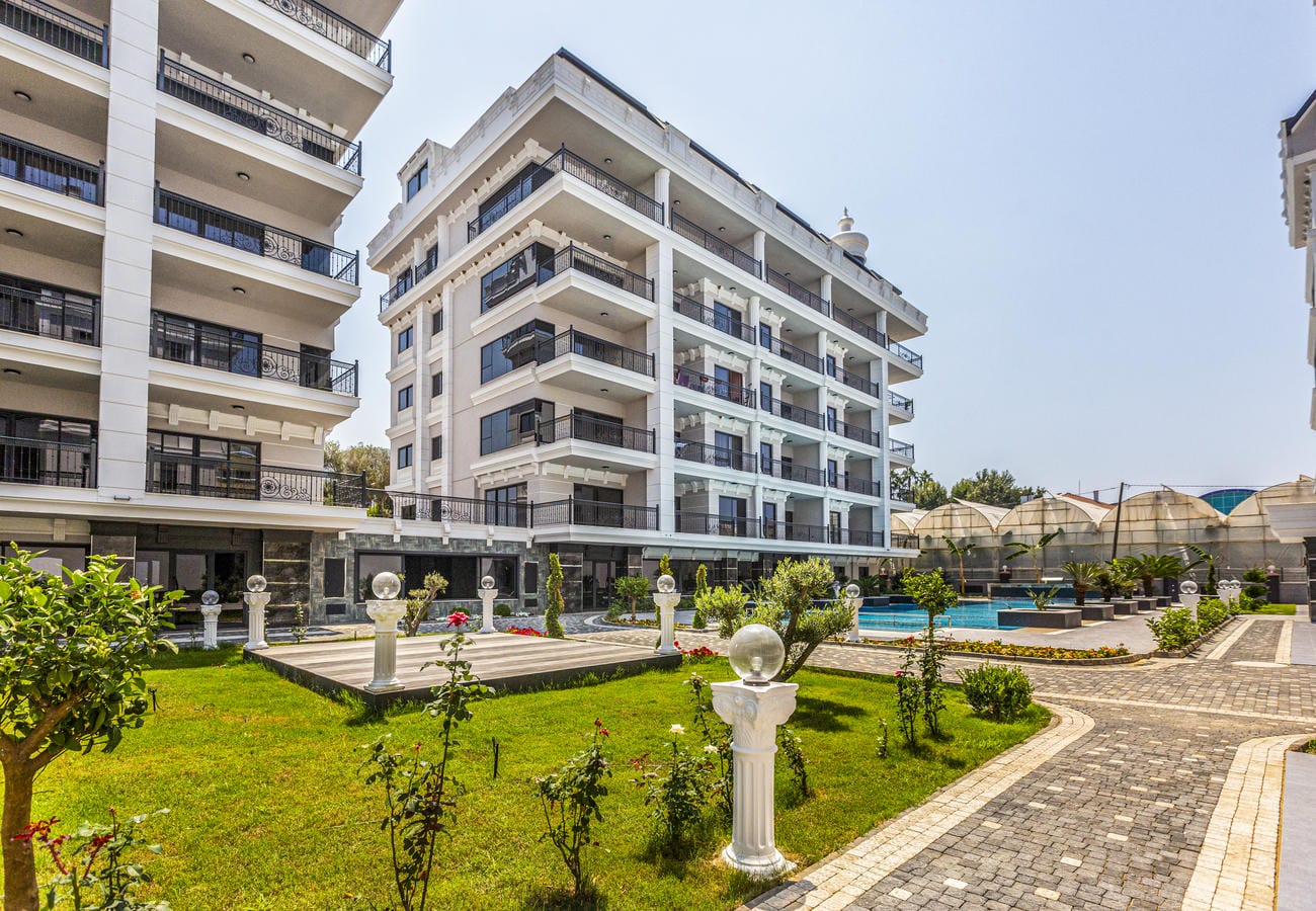Alanya’da Türkiye’de daireli sitede sütunlu dekoratif alanın yanındaki çimli bahçe
