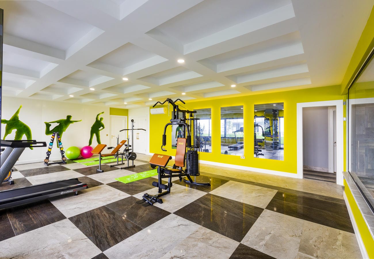Konutlu sitenin spor salonunda koşu bandı, kondisyon bisikleti ve büyük duvar aynası