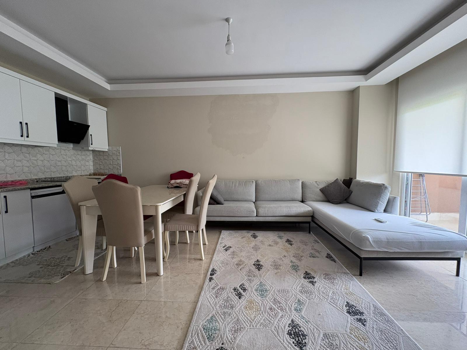Açık renk köşe koltuklu ve balkon çıkışlı mutfaklı salon, Kargıcak’ta