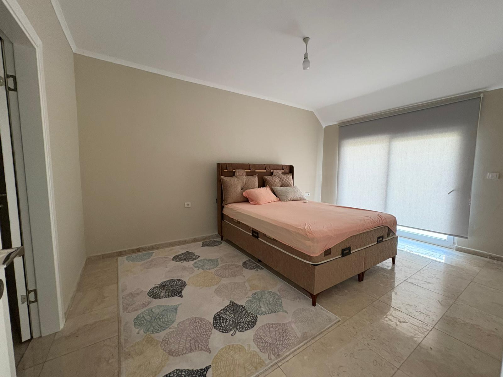 Kahverengi başlıklı ve pembe örtülü çift kişilik yataklı oda, Alanya’daki 3+1 dairede