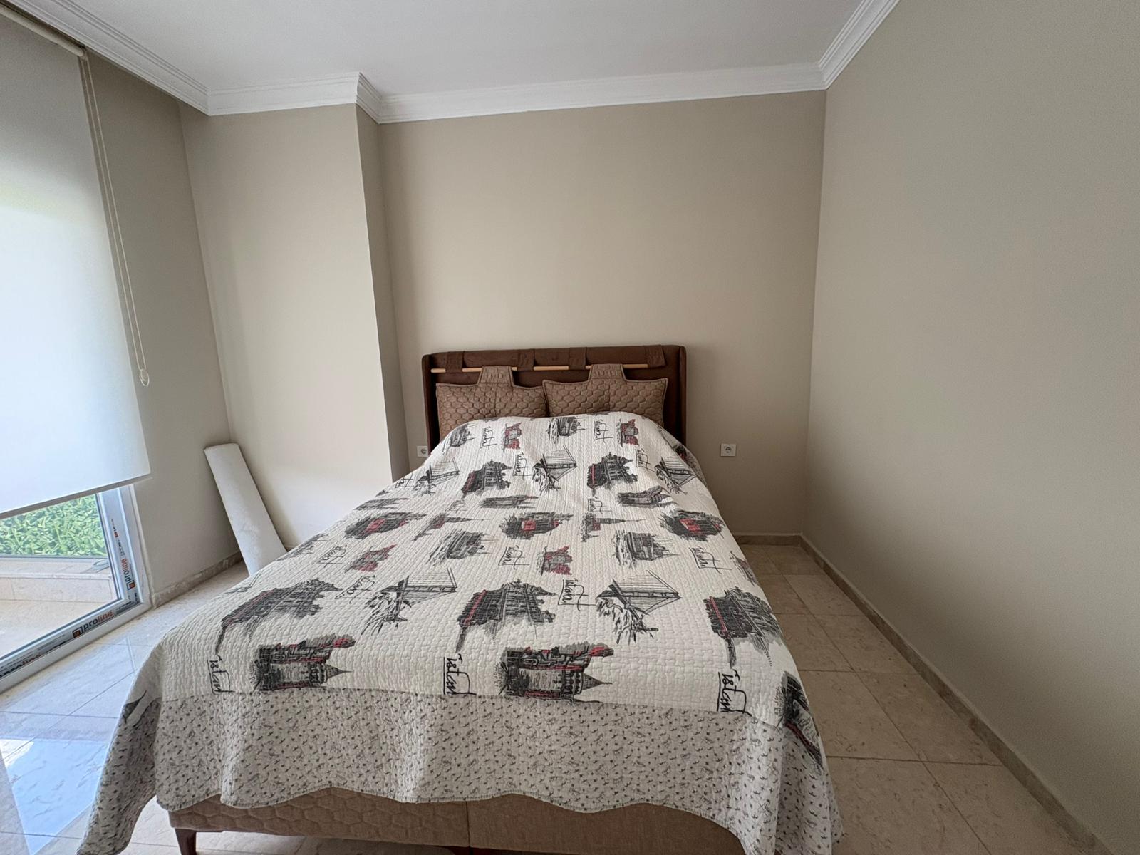 Desenli örtülü yatak ve yeşilliğe bakan pencereli yatak odası, Kargıcak’taki penthouse içinde