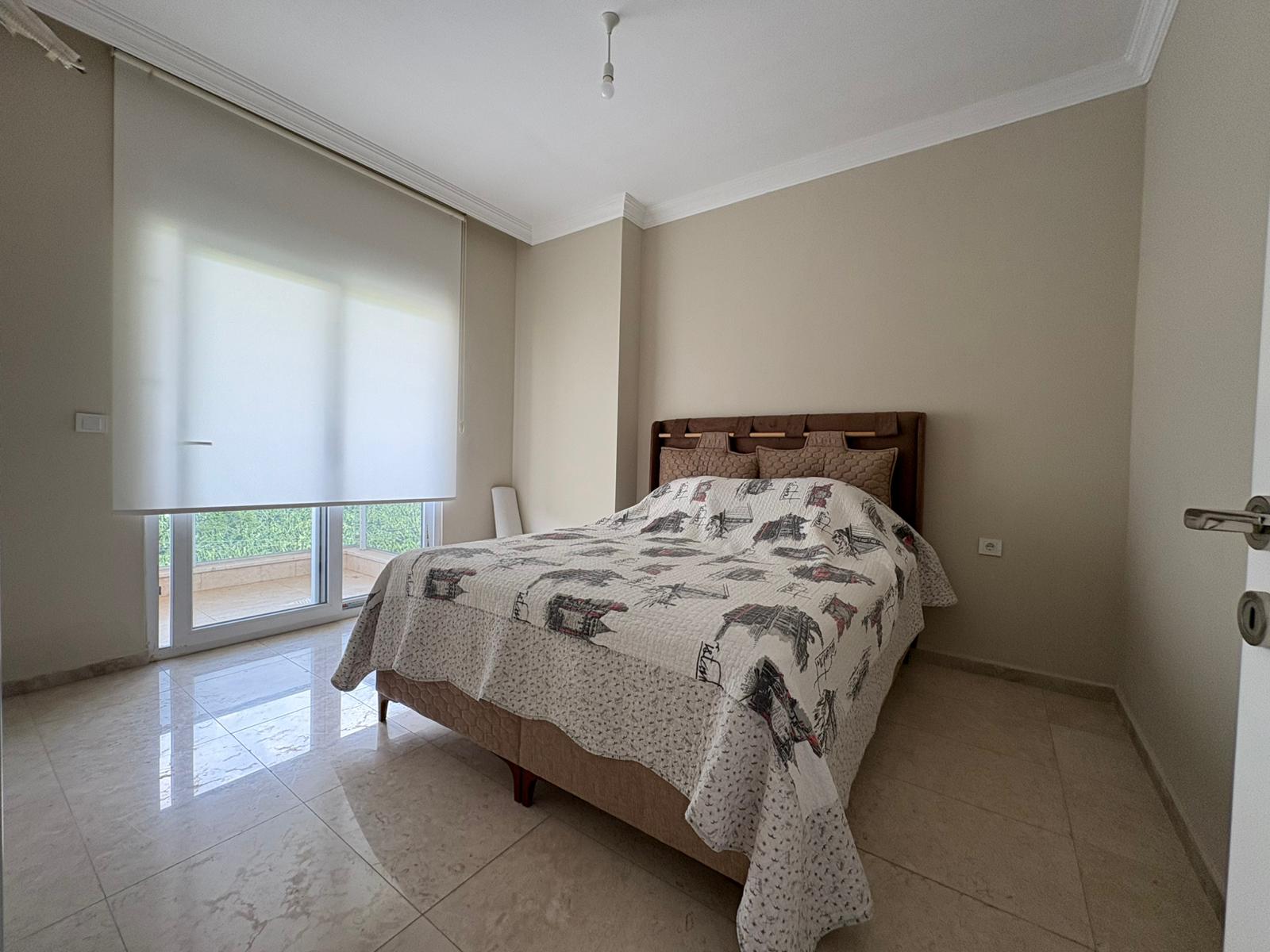 Panoramik pencereden yeşilliğe bakan ve beyaz storlu yatak odası, Alanya’da