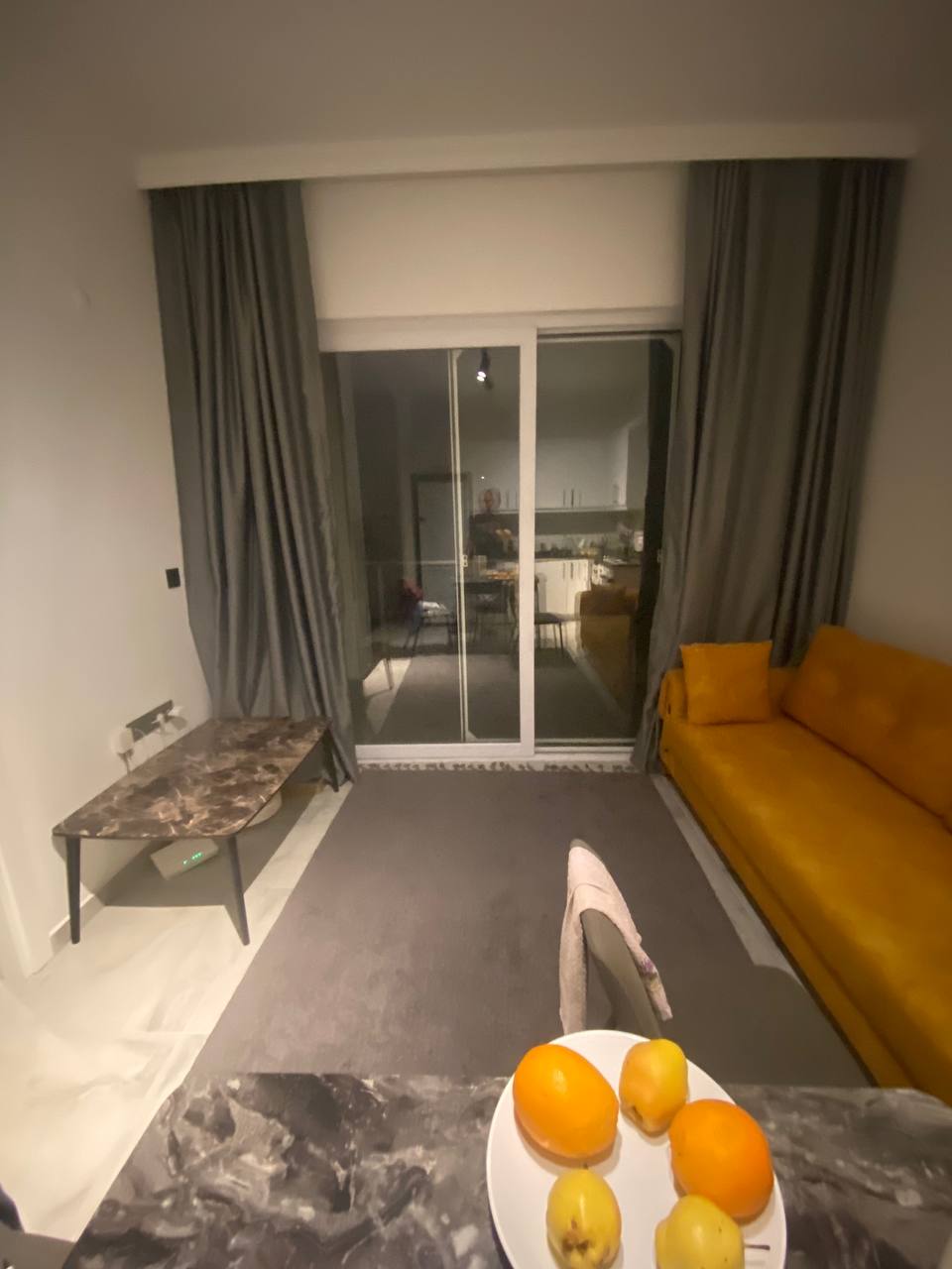 Panoramik cam önündeki hardal koltuklu salon, Avsallar’da satılık konutun gri perdeleriyle birlikte