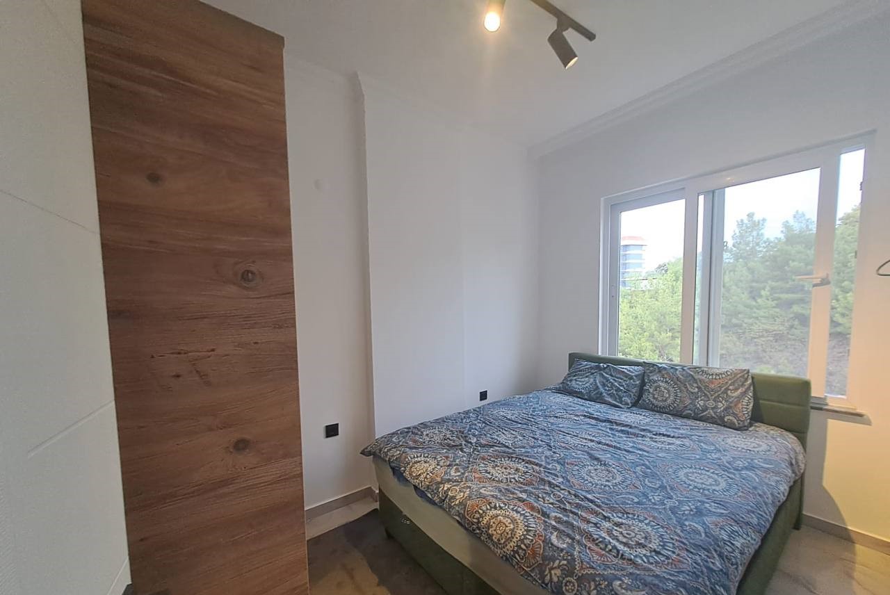 Yeşil başlıklı çift kişilik yataklı yatak odası, Avsallar’da dairedeki panoramik pencere ve ahşap zeminle