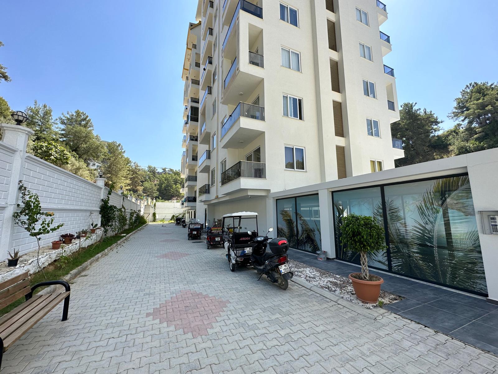 Cam balkonlu beyaz konut bloğu ve iç yol, Avsallar’da Alanya’da Türkiye’de satılık 1+1 daire — New Level Group
