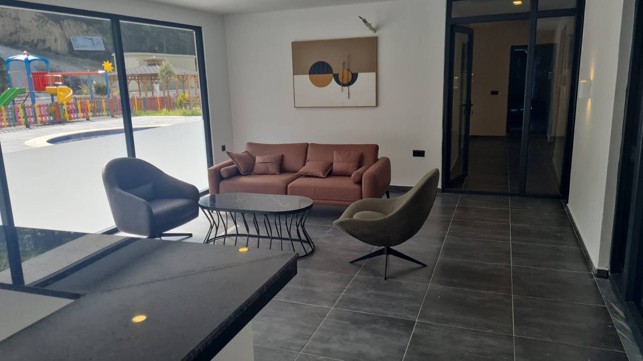 Panoramik cam önündeki köşe koltuklu lobi, Türkiye’deki konutların bulunduğu sitede çocuk alanına bakıyor