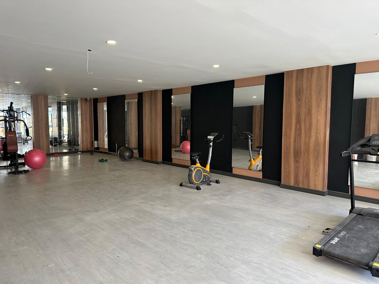 Koşu bandı ve çok işlevli ağırlık aleti bulunan spor salonu, aynalı duvar ve fitness toplarıyla