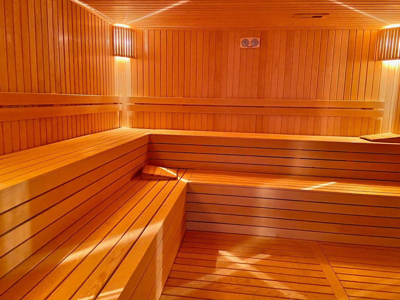 Ahşap kaplamalı sauna, çok katlı raflar ve köşe sediriyle düzenlenmiş