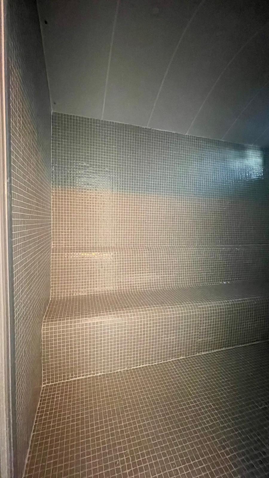 Mozaik duvarlı buhar odasında duvar boyunca mozaik bank ve gömme aydınlatma