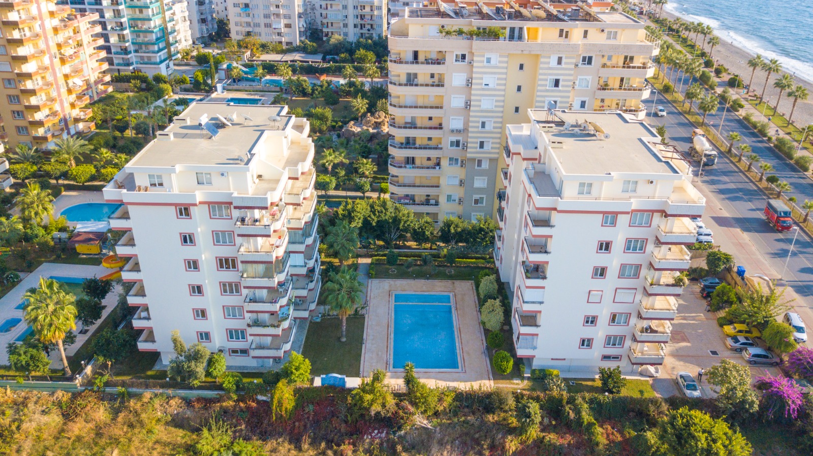 Белые корпуса и бассейн у моря: квартира 2+1 в продаже в Махмутларе, Алания, Турция — New Level Group