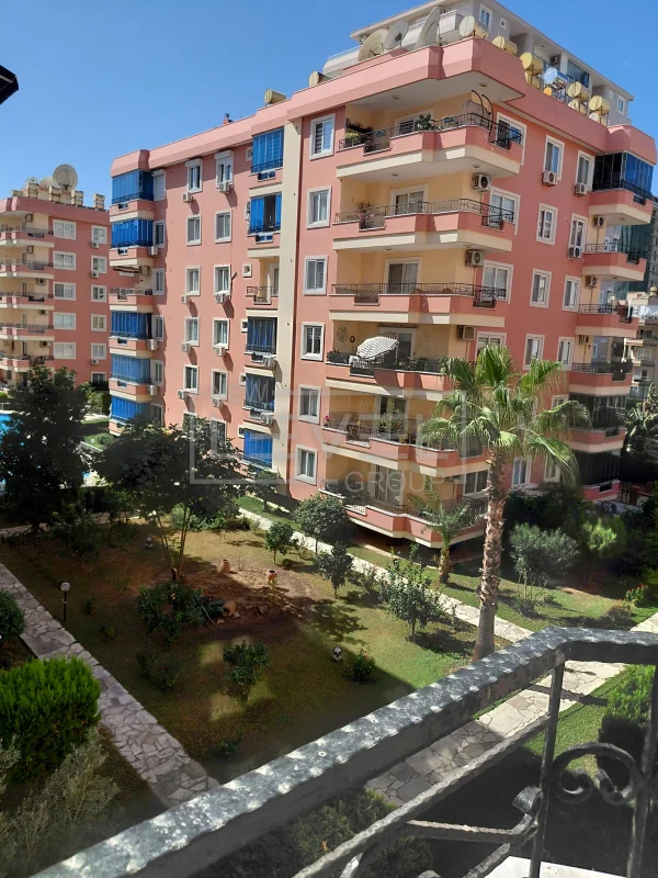 Palmiye ve yürüyüş yollarının bulunduğu satılık dairelerin ortak bahçesi