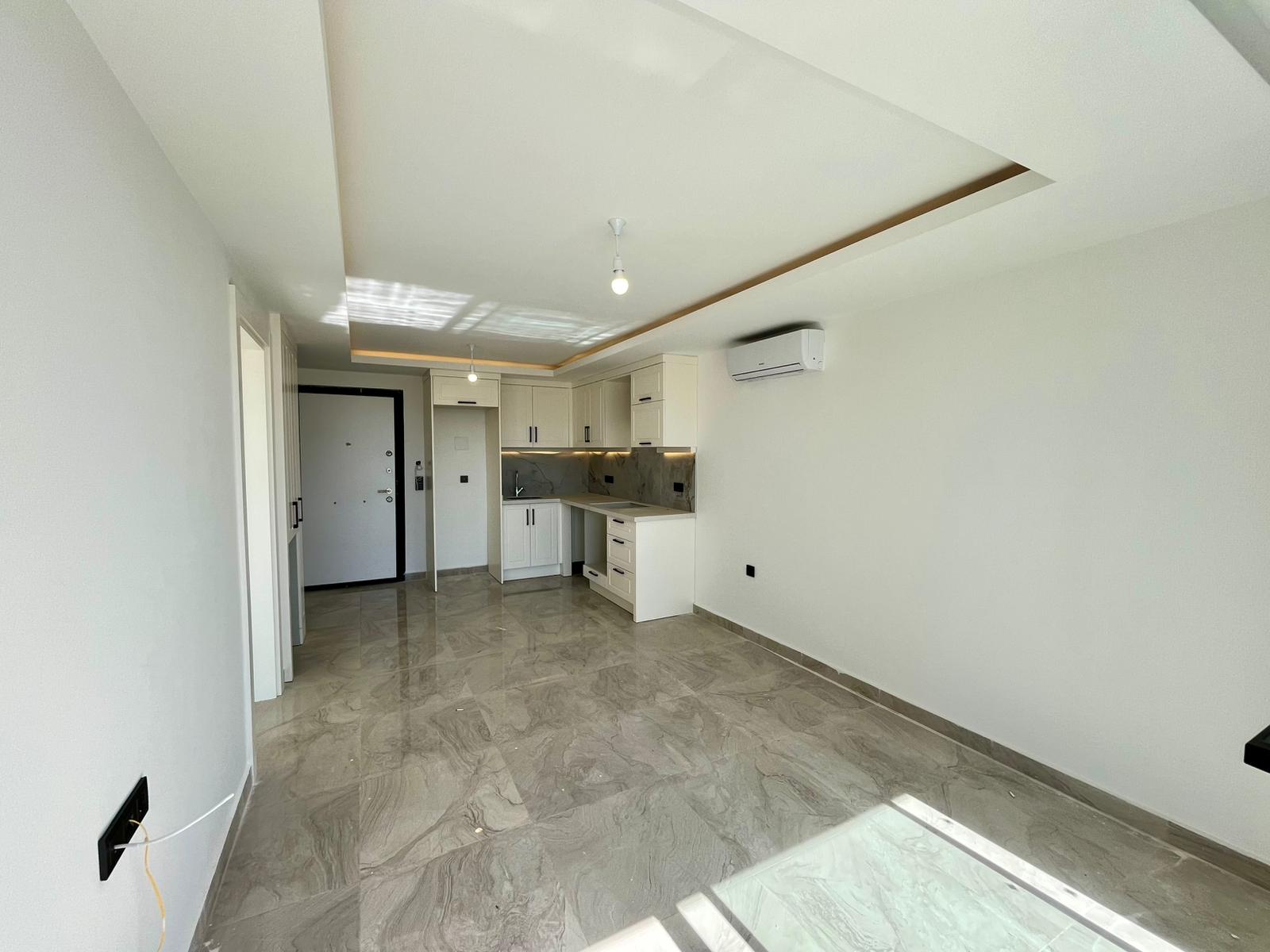 Marble-floored living area with a white kitchen and ceiling lighting in a home for sale