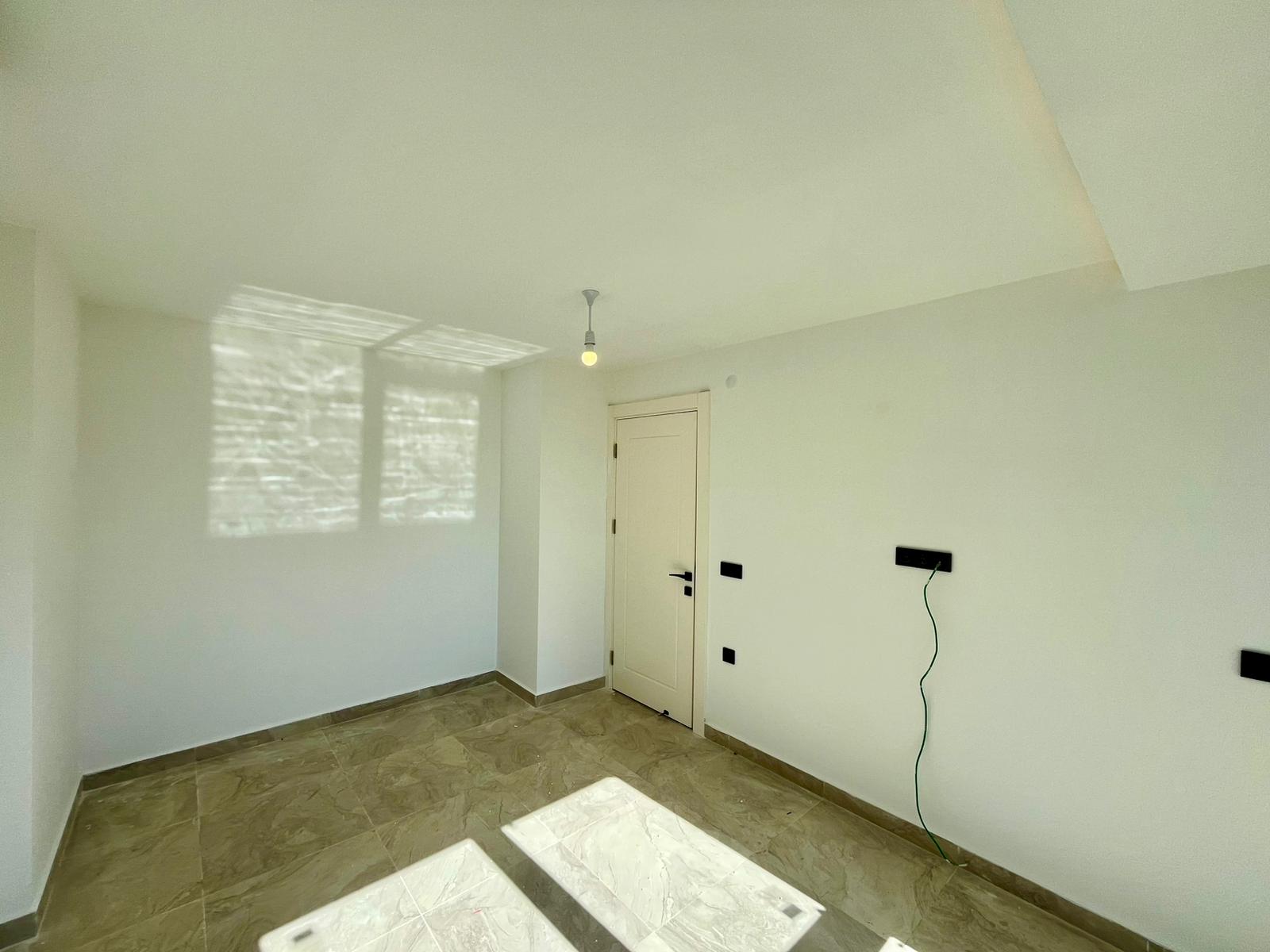 Bedroom with marble-effect flooring and sunlight on the walls in a flat in Alanya